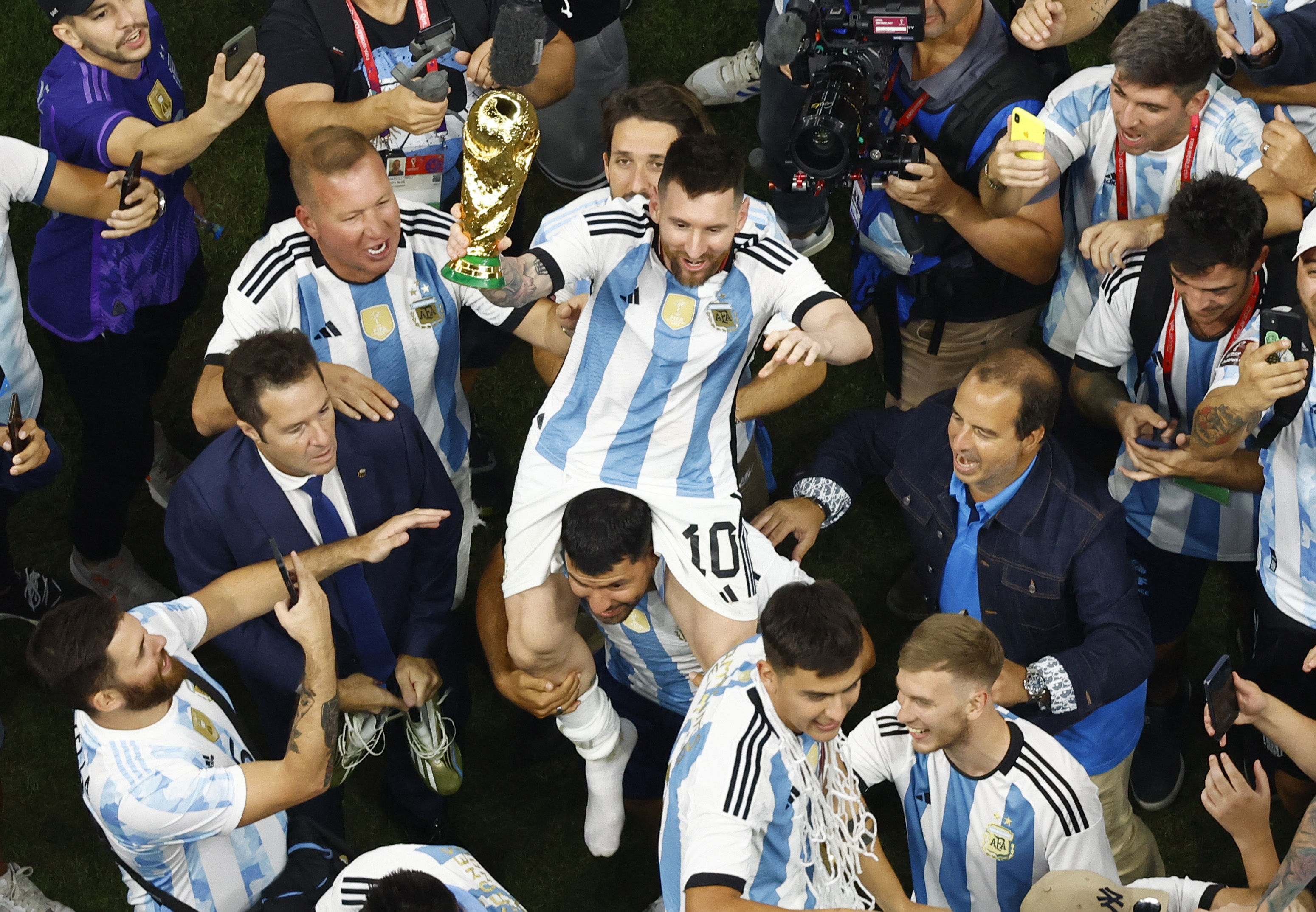 Soccer Football - FIFA World Cup Qatar 2022 - Final - Argentina v France - Lusail Stadium, Lusail, Qatar - December 18, 2022 General view as Argentina's Lionel Messi on the shoulders of Sergio Aguero celebrates with the trophy alongside fans after winning the World Cup REUTERS/Peter Cziborra