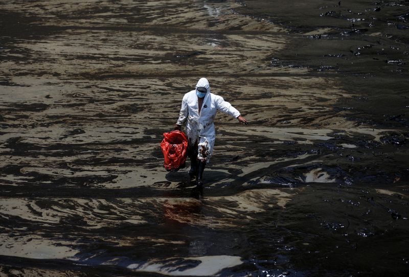 Trabajador en medio de un derrame petrolero en la playa peruana de Ventanilla. REUTERS/Pilar Olivares