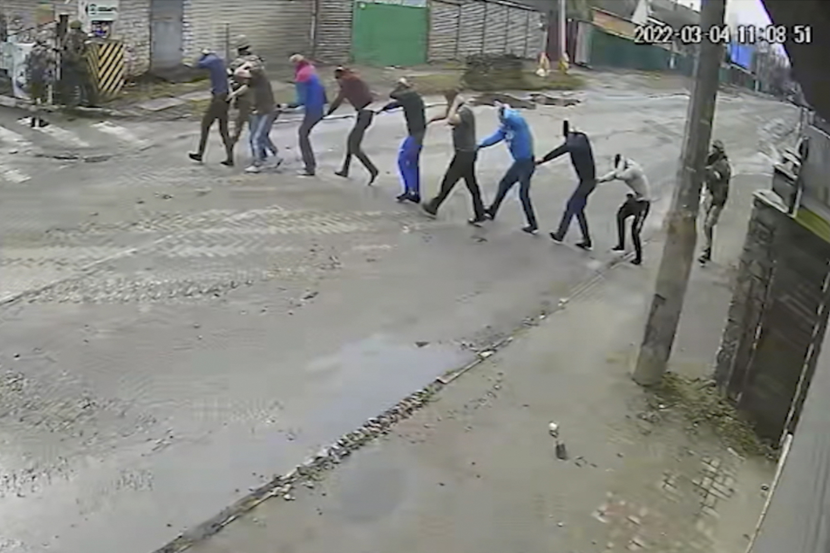 En esta imagen del 4 de marzo de 2022, video de vigilancia proporcionado por el gobierno ucraniano, las tropas rusas conducen a nueve hombres a punta de pistola a su cuartel general en la calle Yablunska en Bucha, donde serían torturados y ejecutados. (Gobierno de Ucrania vía AP)

