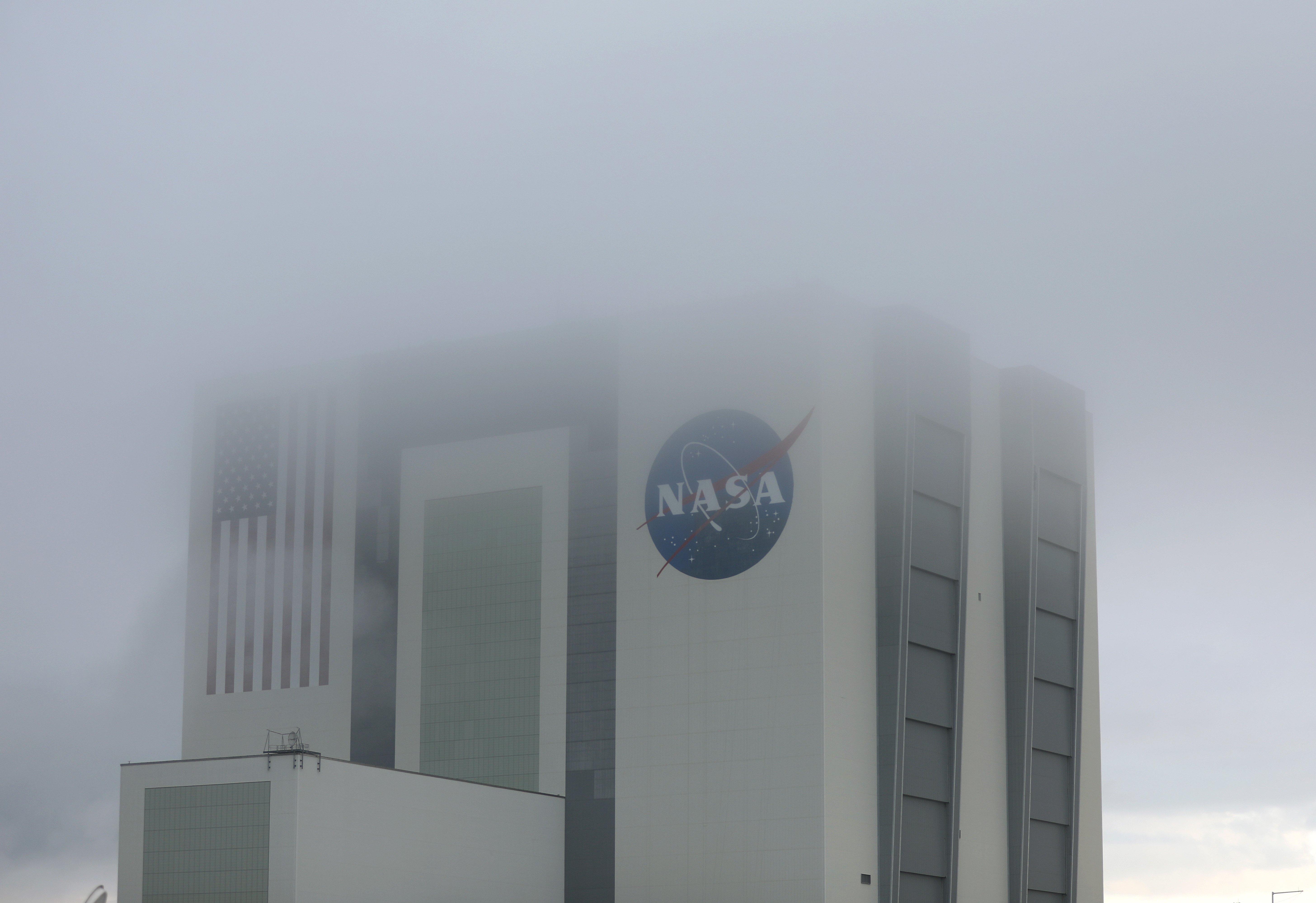 Nubes bajas rodean el edificio de ensamblaje de vehículos de la NASA mientras se prepara para lanzar el cohete SpaceX Falcon 9 con la nave espacial Crew Dragon acoplada desde la plataforma de lanzamiento 39A en el Centro Espacial Kennedy el 27 de mayo de 2020 en Cabo Cañaveral, Florida (Joe Raedle/Getty Images/AFP)