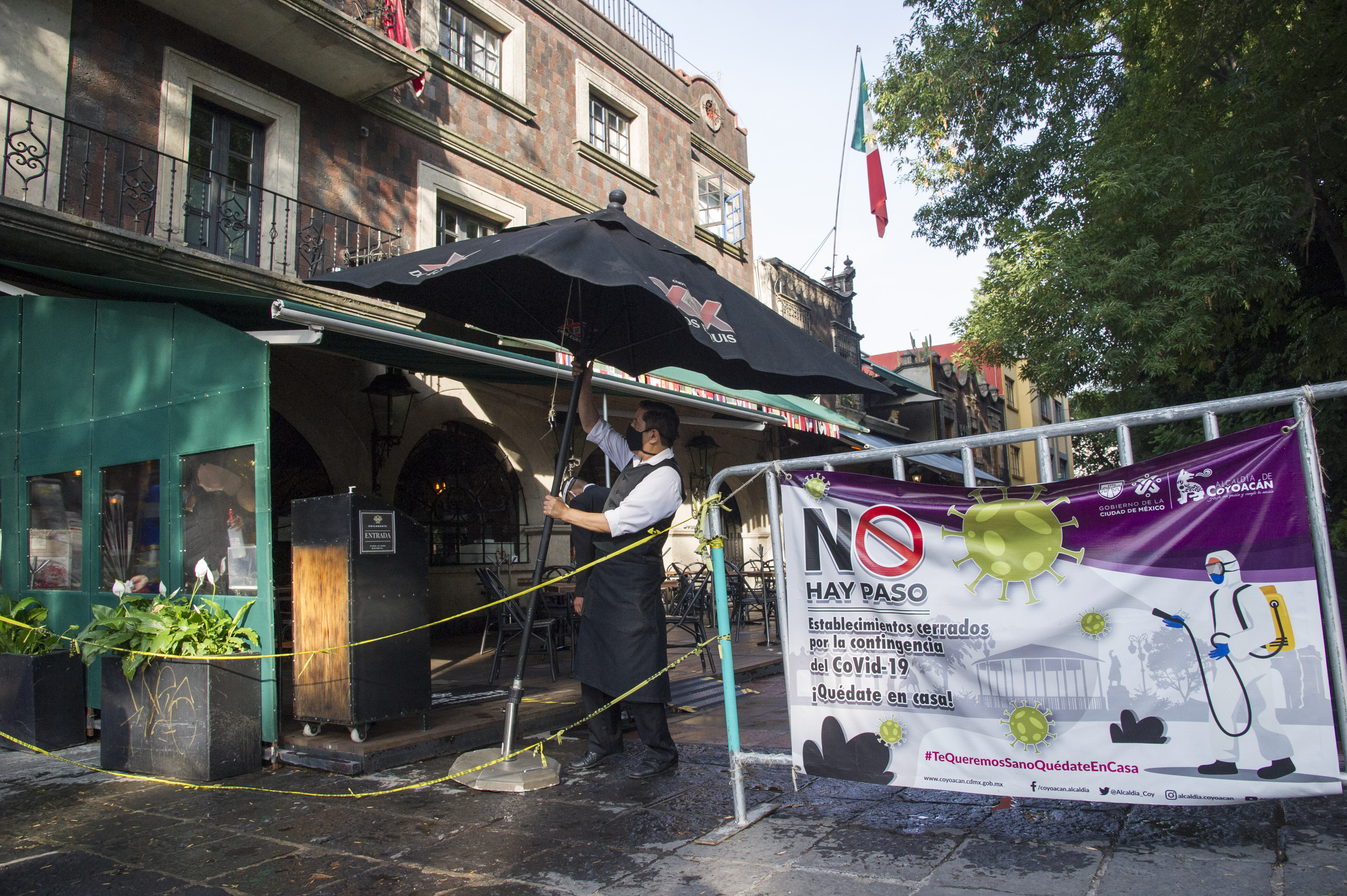 Un trabajador de un restaurante abre una sombrilla en el barrio de Coyoacán, Ciudad de México, el 1 de julio de 2020 durante la pandemia de COVID-19. (Foto: CLAUDIO CRUZ / AFP)