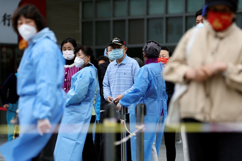 Varias personas con mascarilla esperan en fila para someterse a un test de COVID-19 en el distrito Chaoyang de Beijing, China (REUTERS/TIngshu Wang)