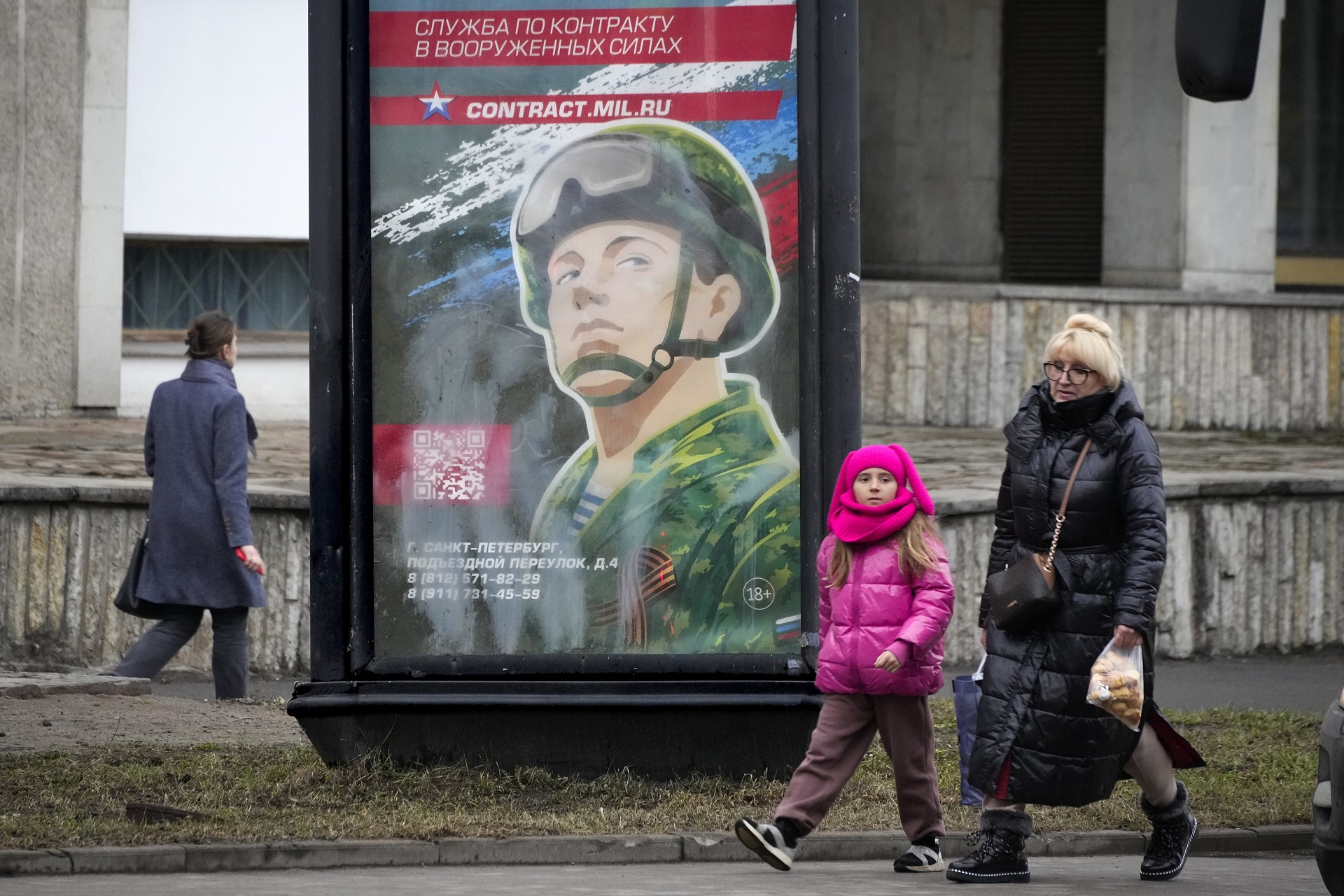 Peatones junto a un cartel de campaña de reclutamiento en San Petersburgo (AP)