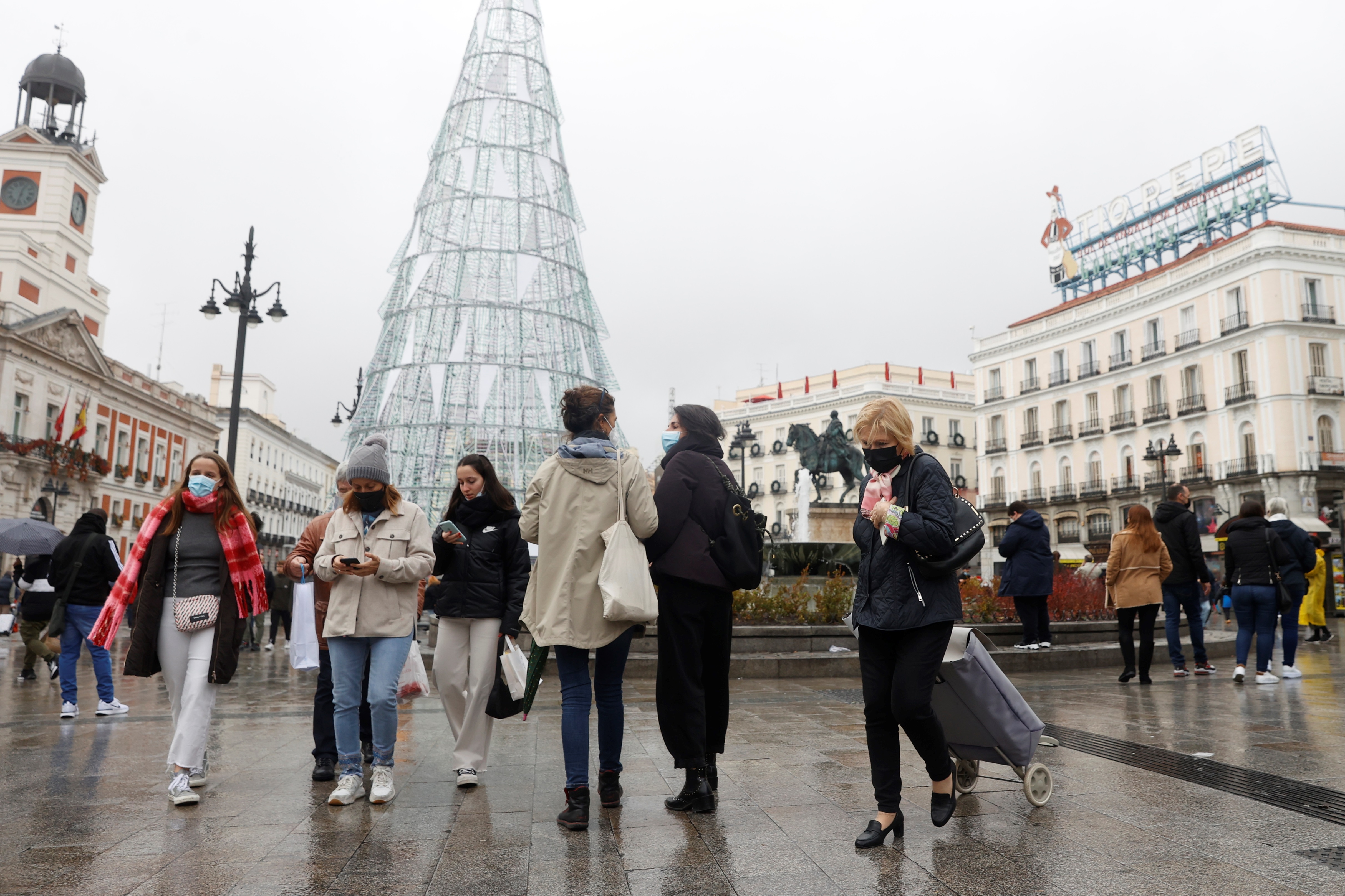 Varias personas caminan con mascarillas por la Puerta del Sol este viernes (EFE/JuanJo Martín)