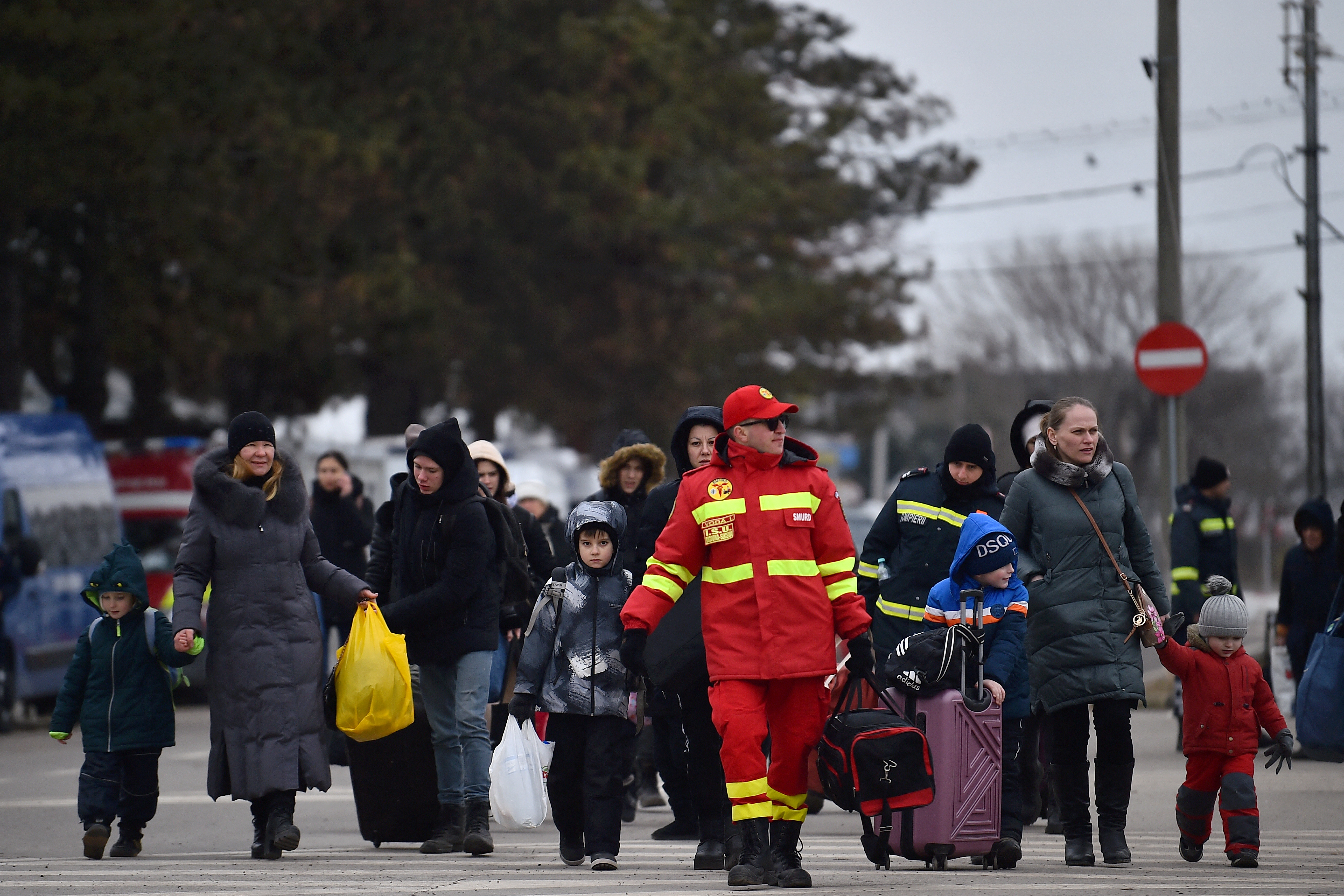 Un vigile del fuoco guida una famiglia di rifugiati dopo essere fuggito dall'Ucraina per la Romania, in seguito all'invasione russa dell'Ucraina, al confine a Siret, Romania, il 13 marzo 2022. REUTERS/Clodagh Kilcoyne