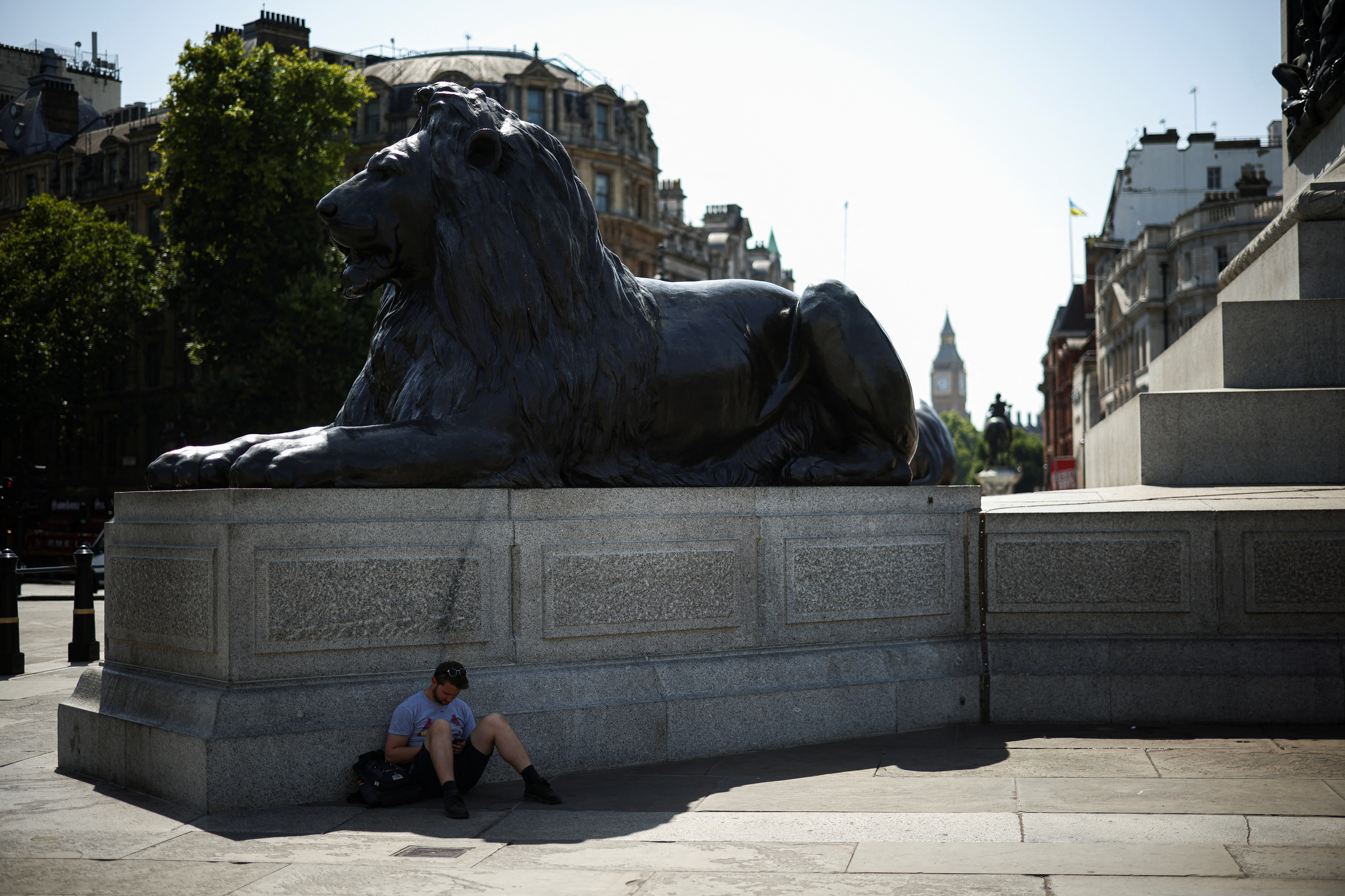 Un hombre se refugia de las altas temperaturas en la sombra de una de las estatuas de Trafalgar Square. Estas temperaturas son "excepcionales" ya que pueden tener impacto "en las personas y la infraestructura", indicó la agencia meteorológica. 