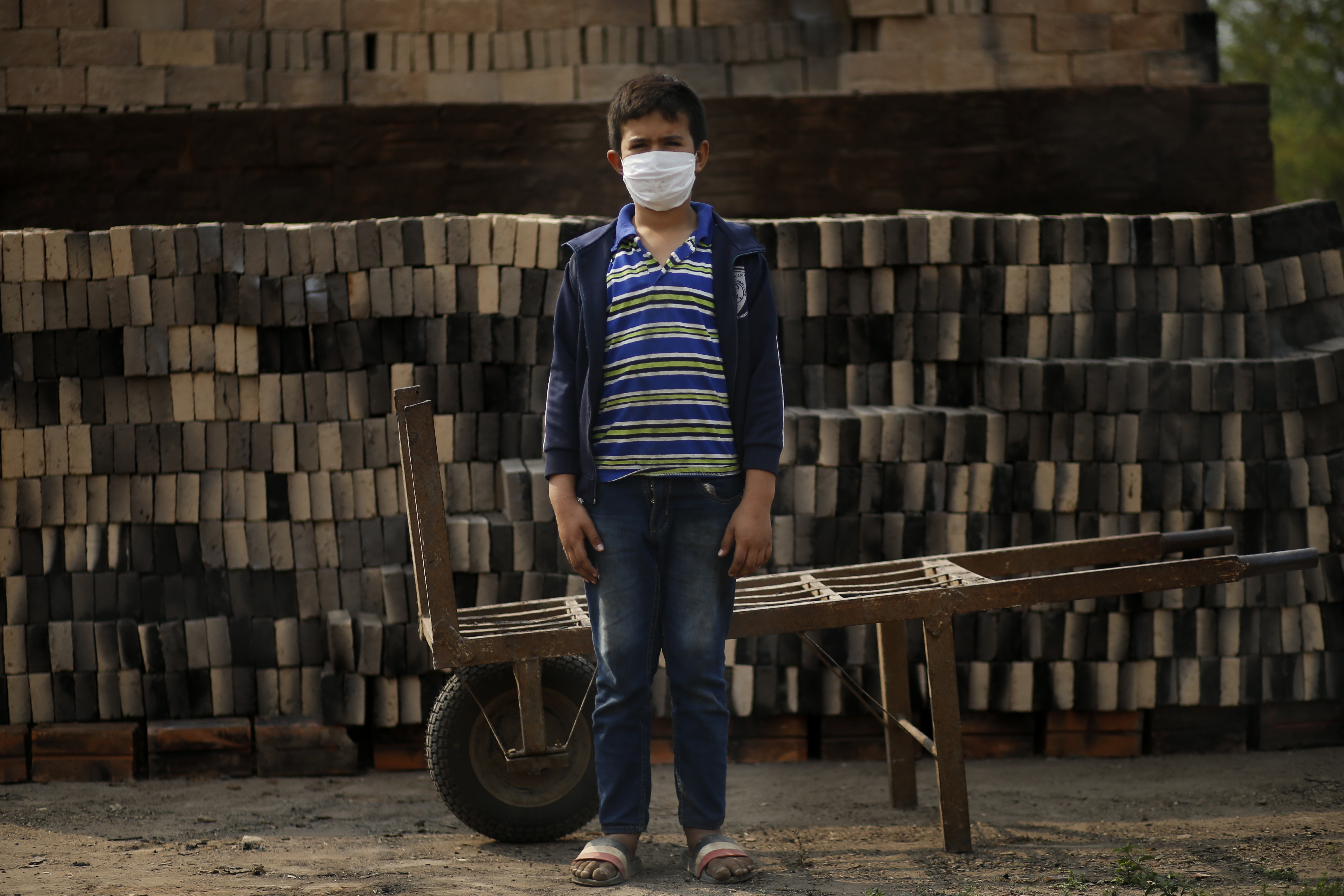 Ronnie, de 10 años, con una máscara para frenar la propagación del nuevo coronavirus, posa para un retrato mientras trabaja junto a su padre en una pequeña fábrica de ladrillos en Tobati, Paraguay, el lunes 31 de agosto de 2020.