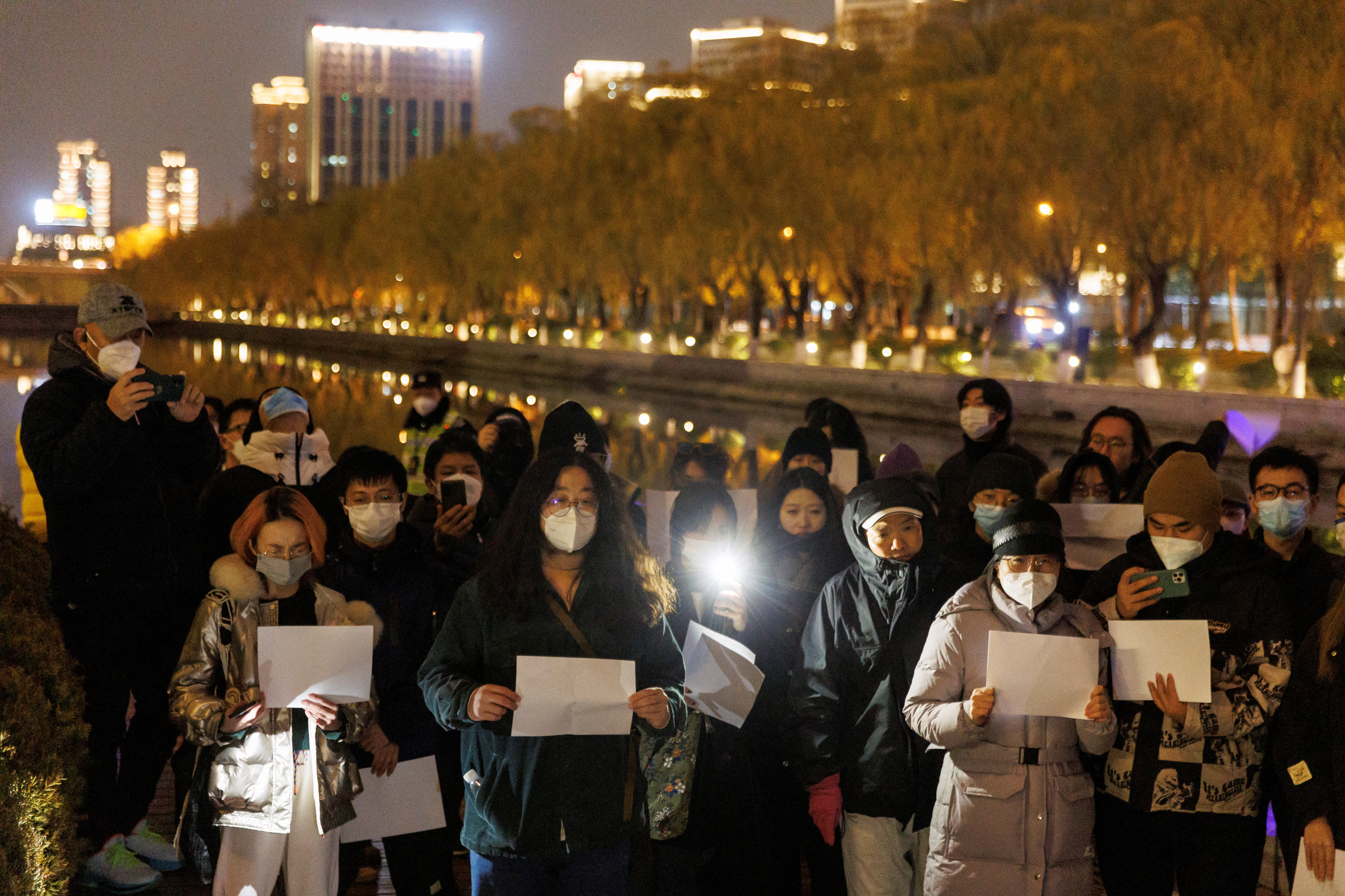 La gente se reúne para una vigilia y sostiene hojas de papel blanco en protesta por las restricciones de la enfermedad del coronavirus (COVID-19), durante una conmemoración de las víctimas de un incendio en Urumqi, mientras continúan los brotes de COVID-19, en Beijing, China, 27 de noviembre de 2022. REUTERS/Thomas Peter