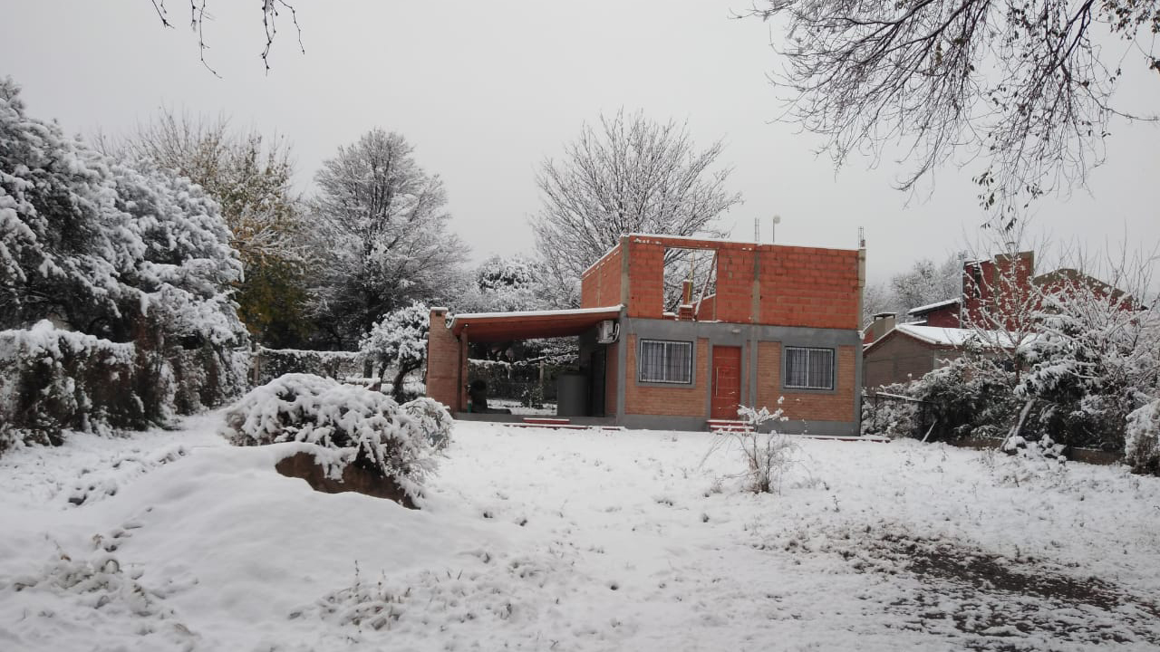 Una casa y el jardín completamente cubiertos de nieve en San Roque, Córdoba