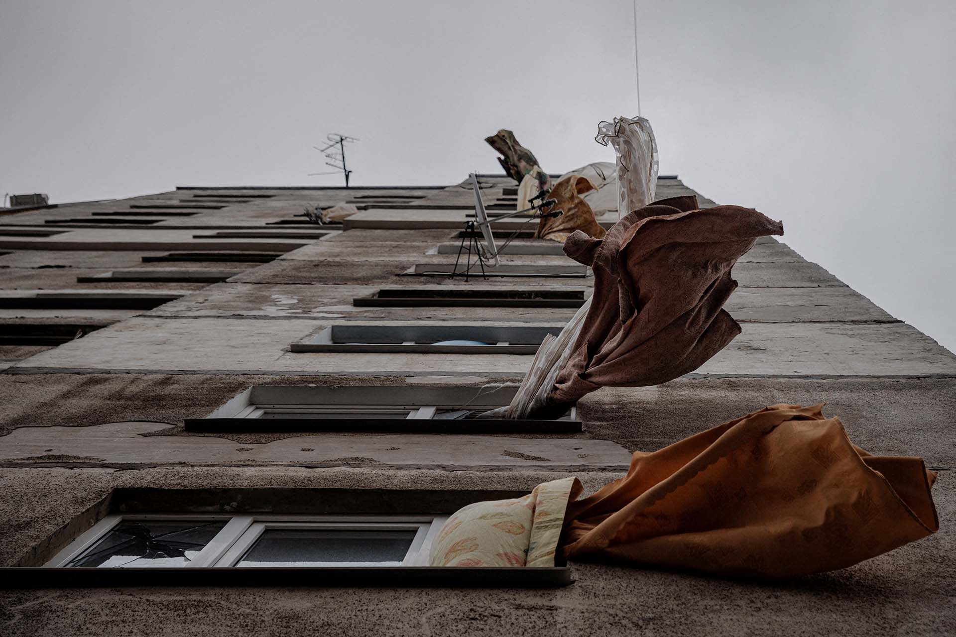 Cortinas flameando con el viento desde las ventanas de un edifico asolado por los bombardeos rusos, en un barrio casi fantasma, que fue abandonado por sus habitantes y dejado sin agua ni gas, en Kharkiv (REUTERS/Thomas Peter)