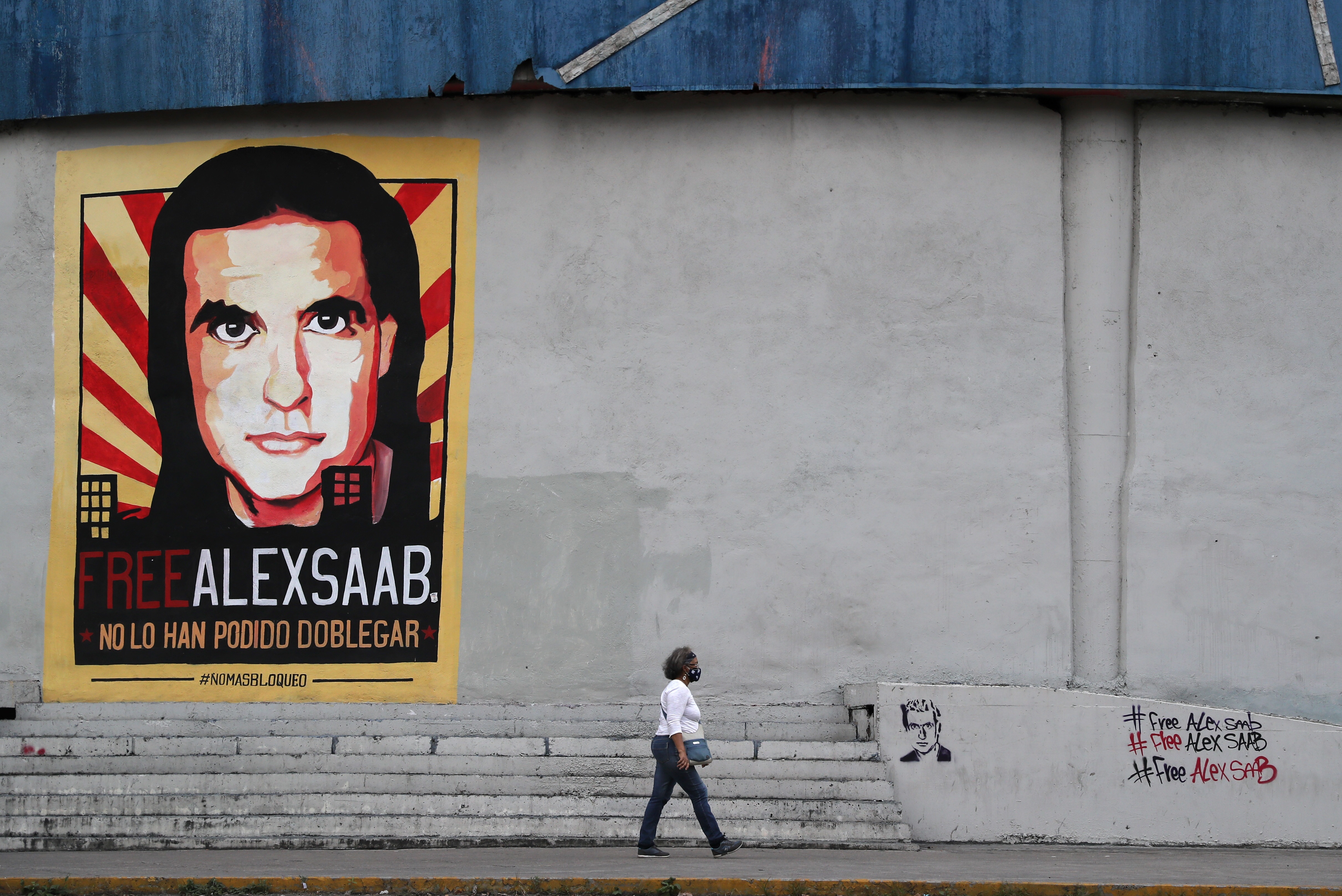 Una mujer pasa frente a un cartel de Alex Saab en Caracas