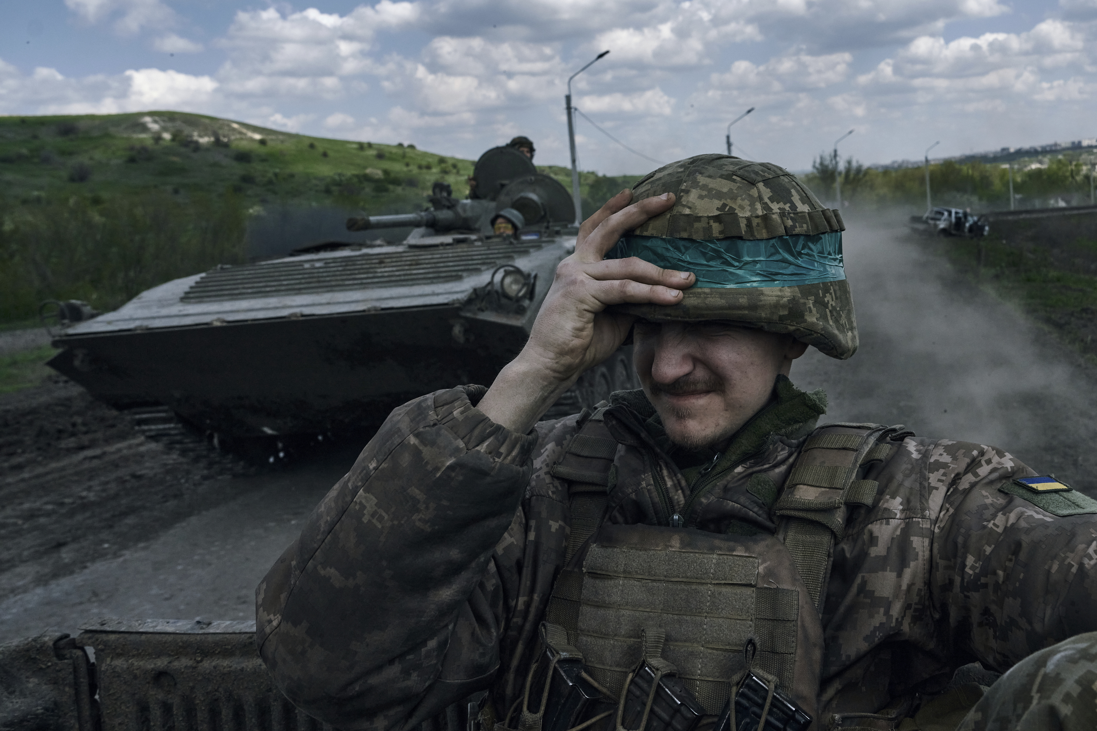 Un soldado ucraniano se agarra el casco mientras viaja a bordo de un APC en la zona de Bakhmut  (AP Foto/Libkos)