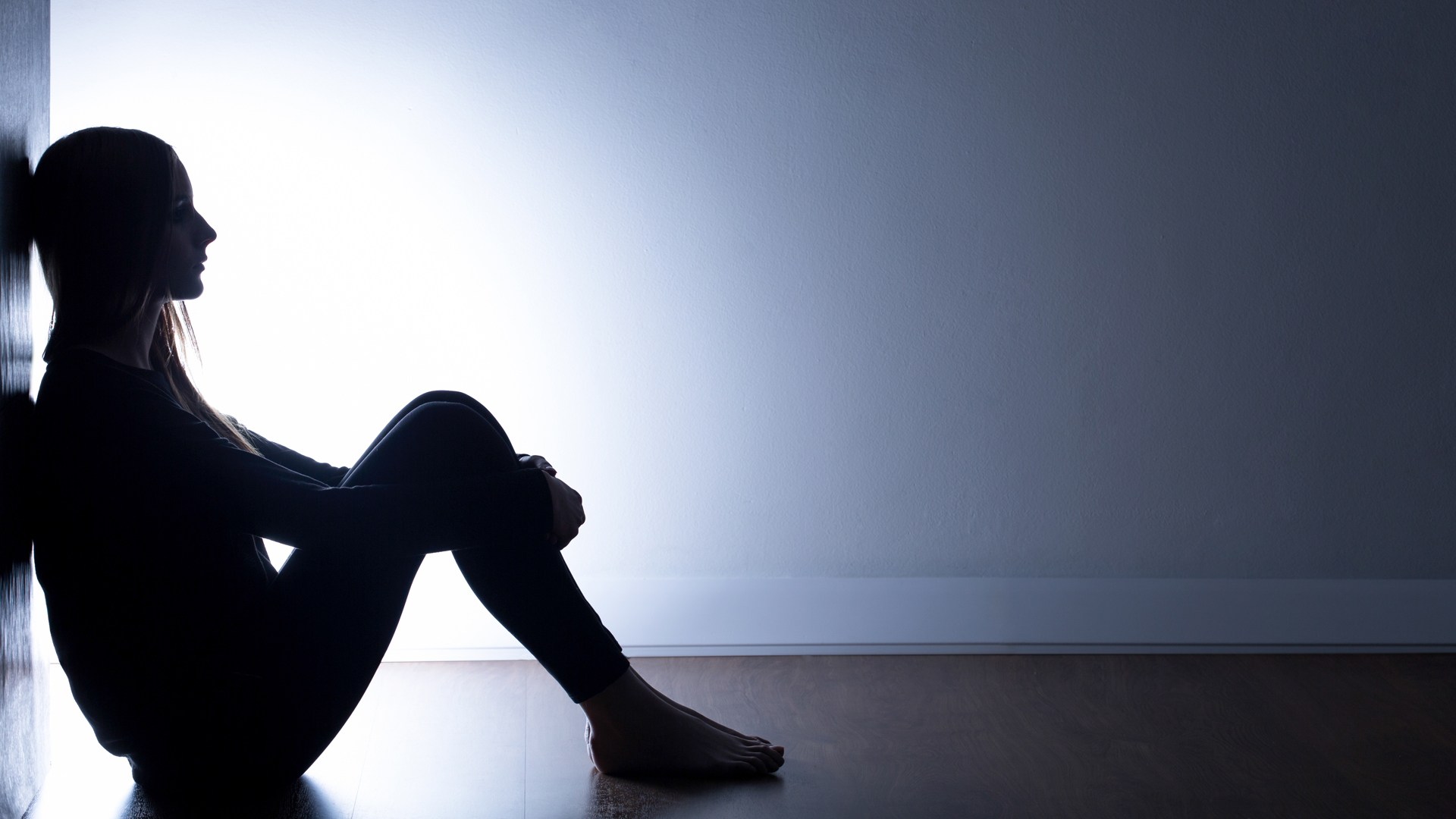 Teenager with depression sitting alone in dark room