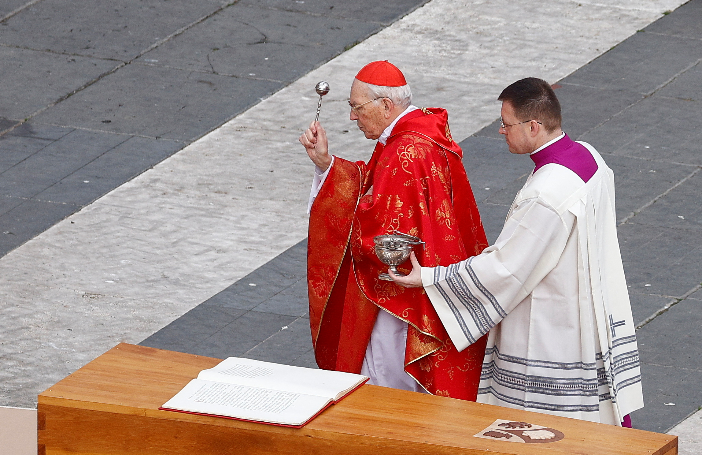 El cardenal Giovanni Battista bendice el ataúd con agua bendita en el final de la ceremonia.