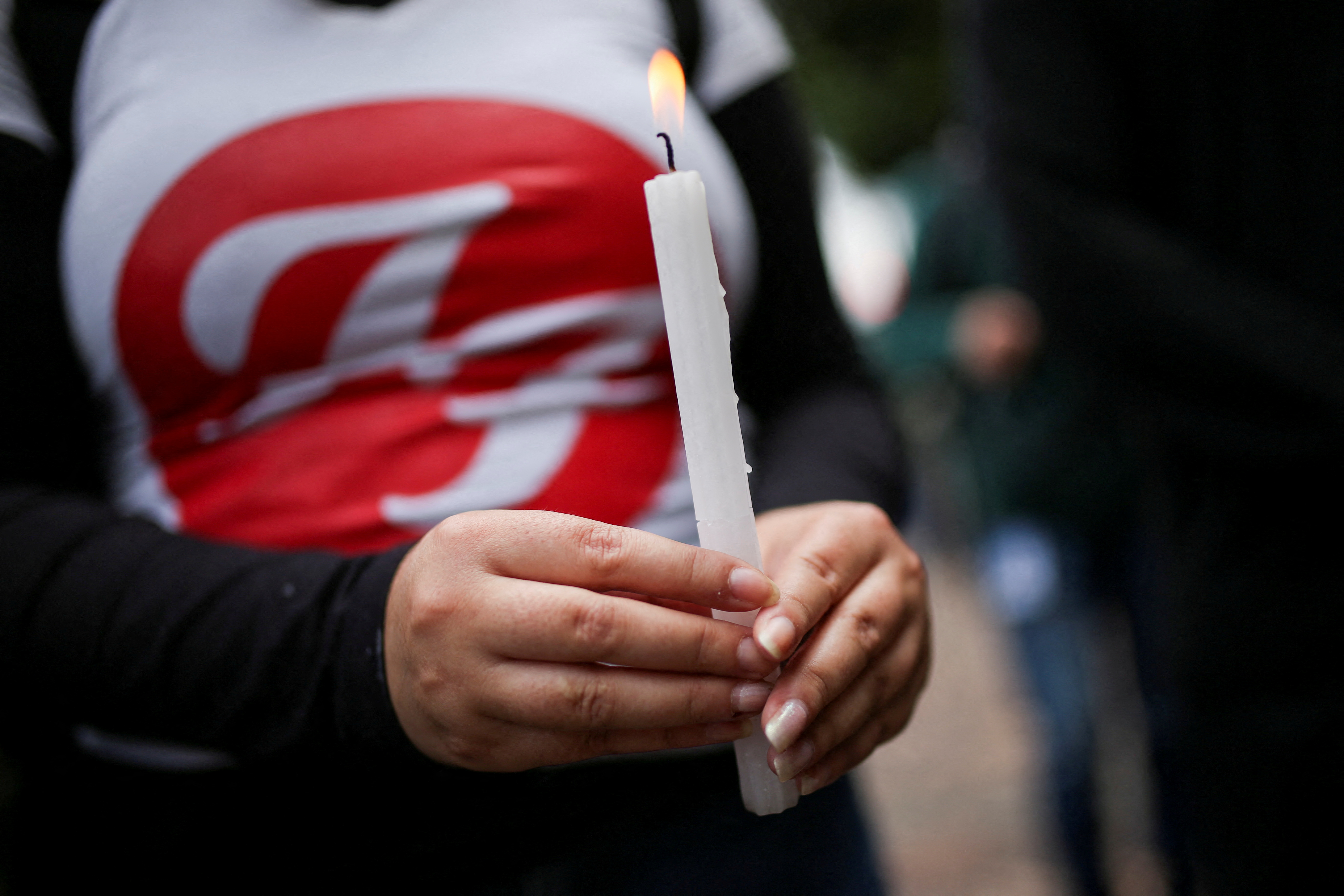 A woman holds a candle outside the Casa Medina hotel where Taylor Hawkins, the band's drummer, died before appearing at the Estereo Picnic festival in Bogota, Colombia March 26, 2022. REUTERS/Luisa Gonzalez REFILE - CORRECTING INFORMATION