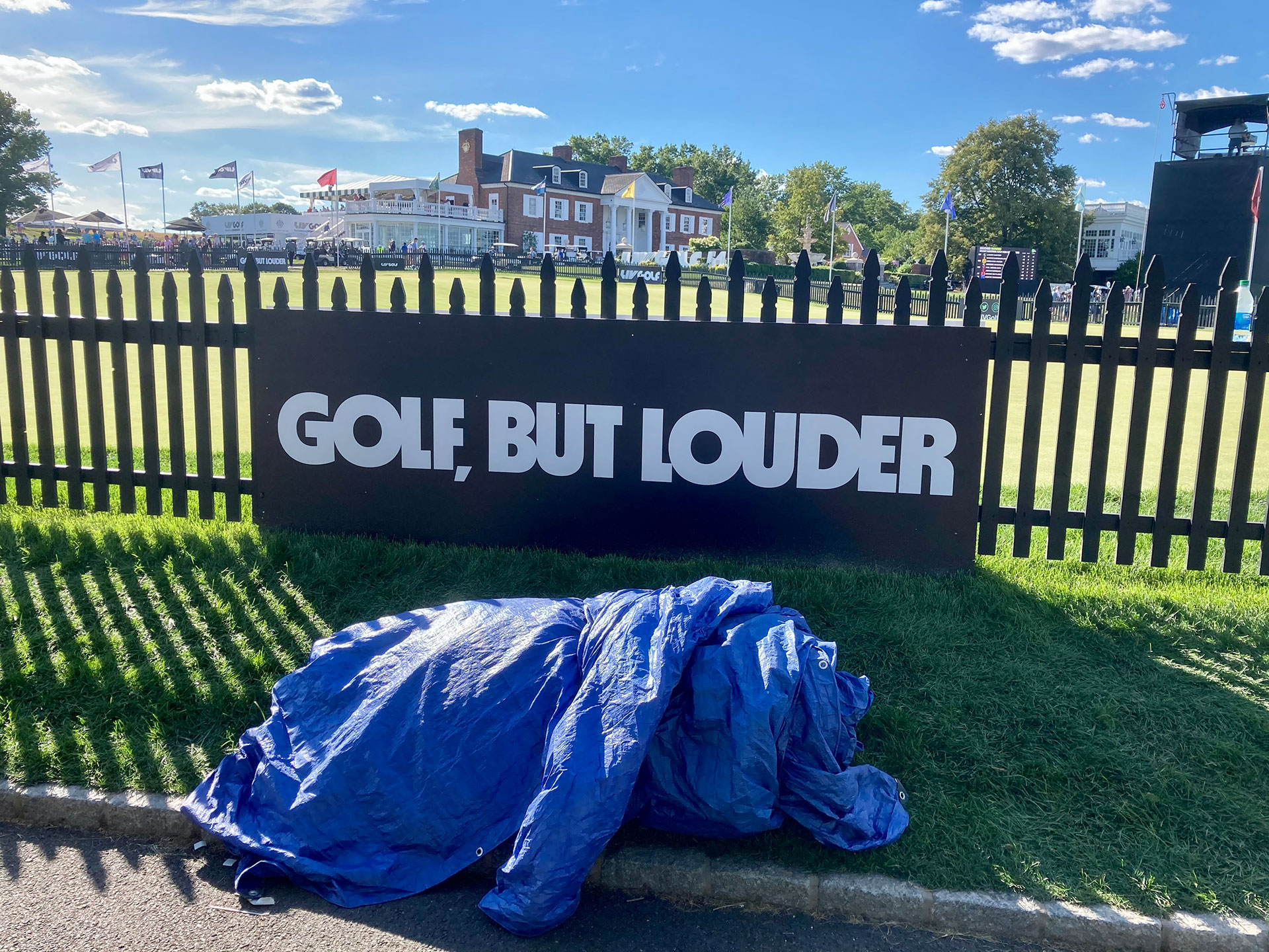 The slogan of the LIV Golf Tour is displayed prominently as the clubhouse at Trump National Golf Club Bedminster is seen in the background