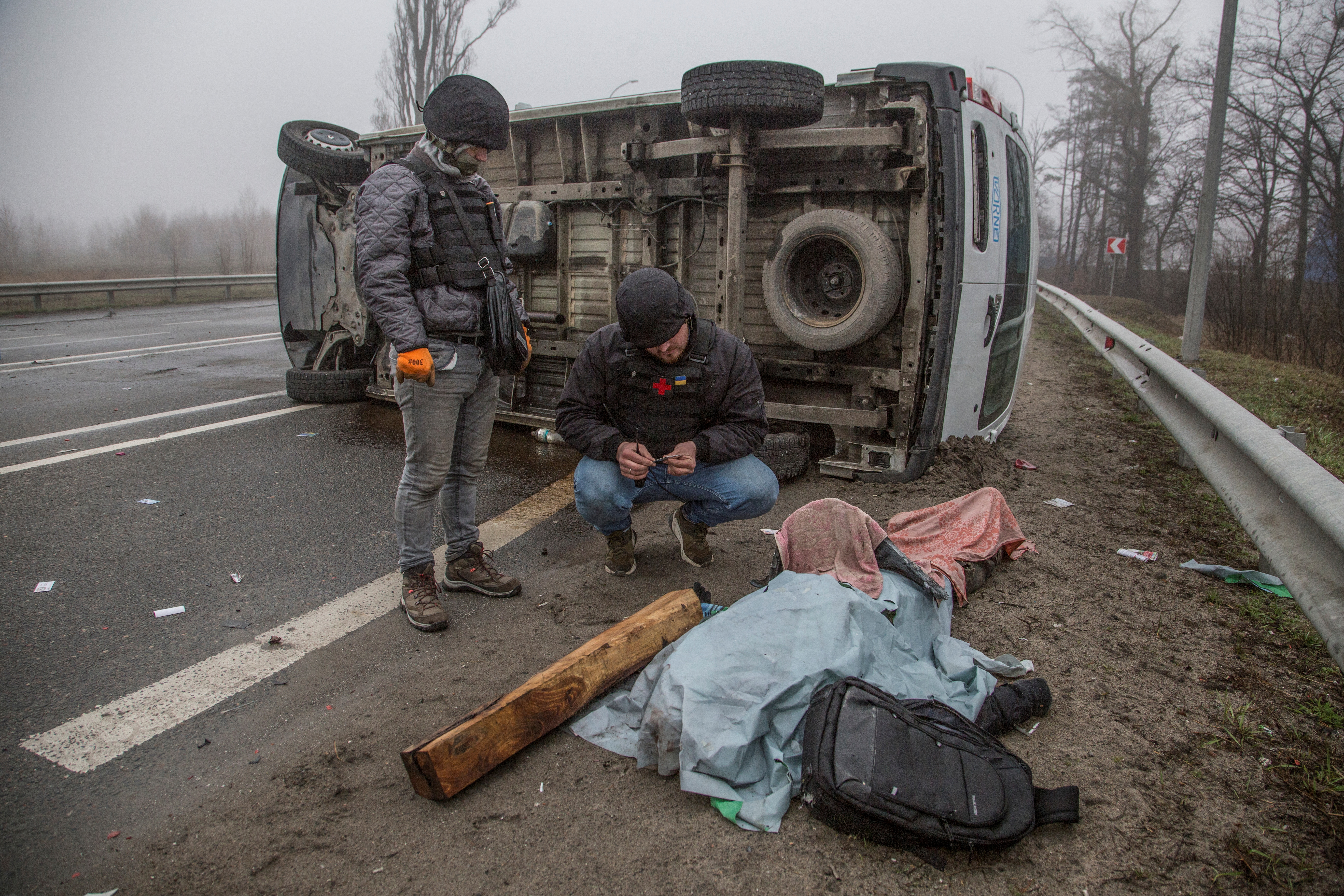 Voluntarios observan un cuerpo en una calle de Bucha (REUTERS/Oleksandr Ratushniak)