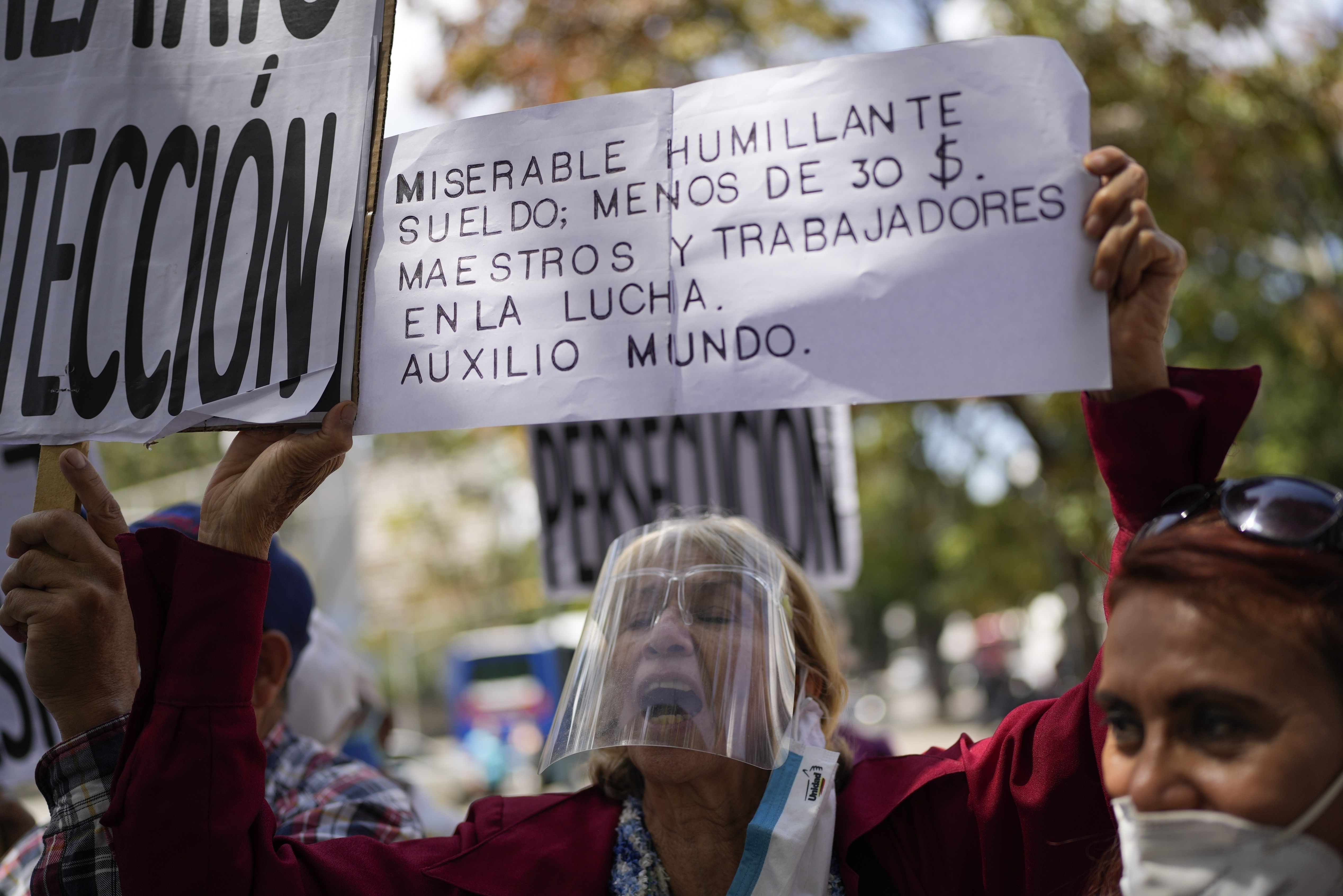 ARCHIVO - Una mujer sostiene un cartel durante una protesta en reclamo de un aumento en las pensiones en medio de una inflación récord mundial en Caracas, Venezuela, el 15 de febrero de 2022. (AP Foto/Ariana Cubillos, Archivo)