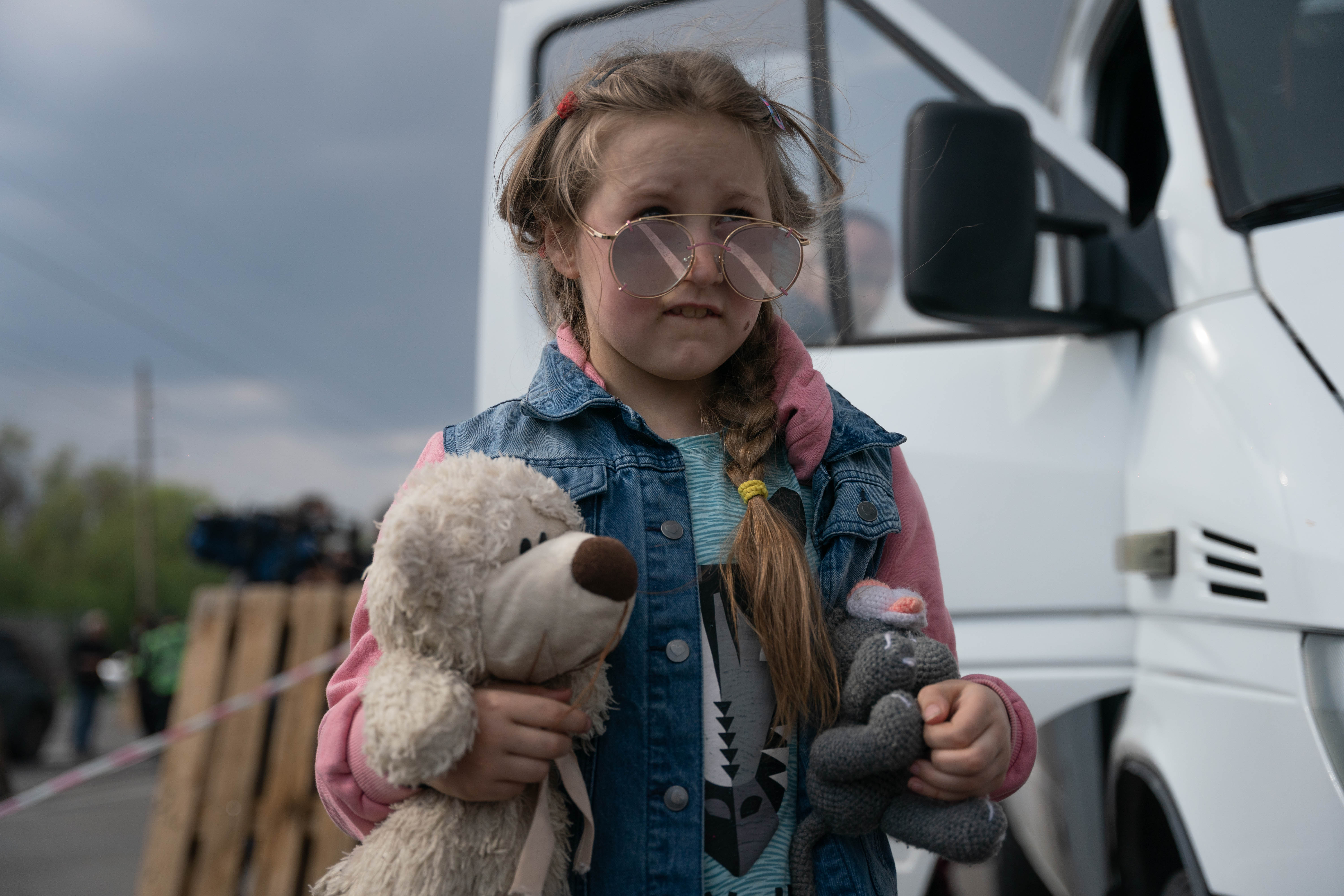 Una niña con los anteojos de su padre y sus dos peluches espera en el centro de asistencia de Zaporizhzhia, tras recorrer 230 kilómetros durante tres días para escapar de Mariupol (Foto: Franco Fafasuli)