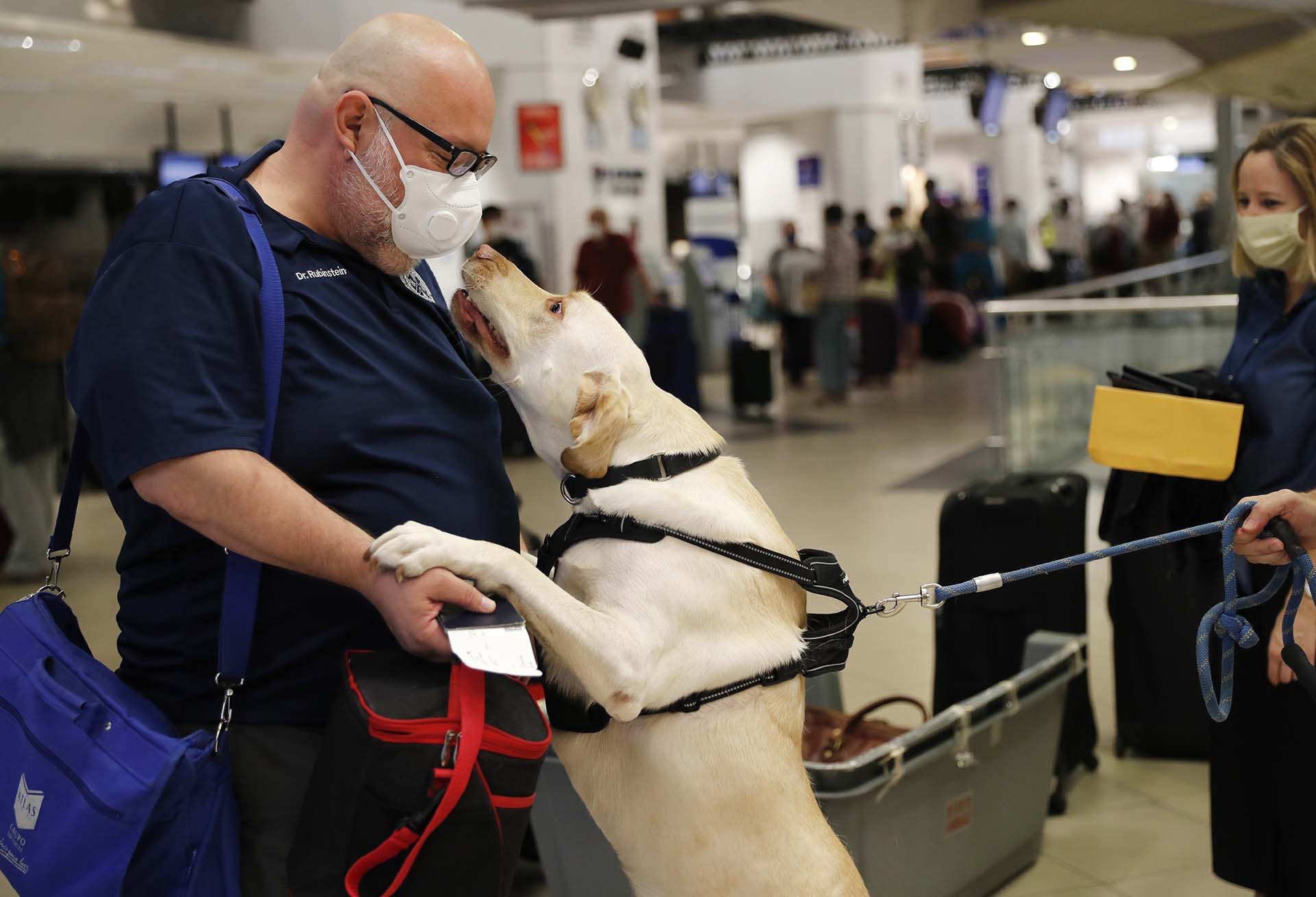 El doctor Rubinstein recibe un salido de un perro llamado Dumas mientras los pasajeros se preparan para tomar un vuelo a Miami desde el aeropuerto de Asuncion, Paraguay (AP Photo/Jorge Saenz)