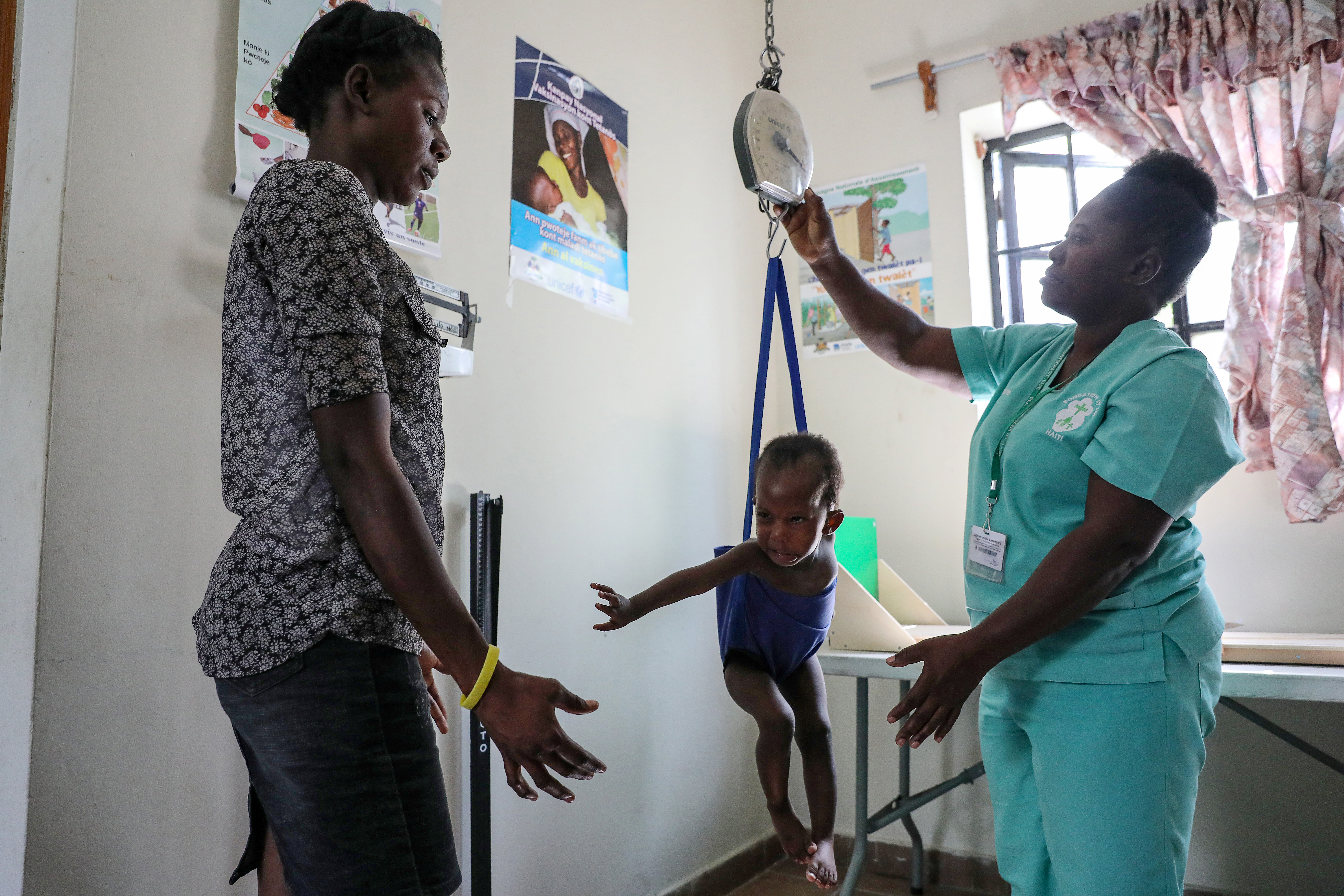 Una enfermera toma el peso de un bebé ante su madre en el hospital St. Luke de Puerto Príncipe (REUTERS/Valerie Baeriswyl)