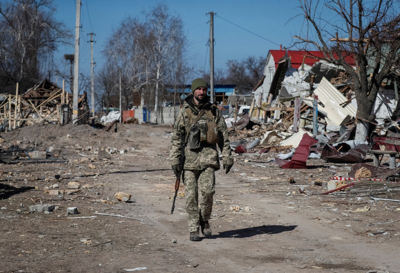 Miembro del servicio de Ucrania camina en un pueblo destruído en la región del este de Kiev, Ucrania, 21 de marzo 2022. REUTERS/Gleb Garanich