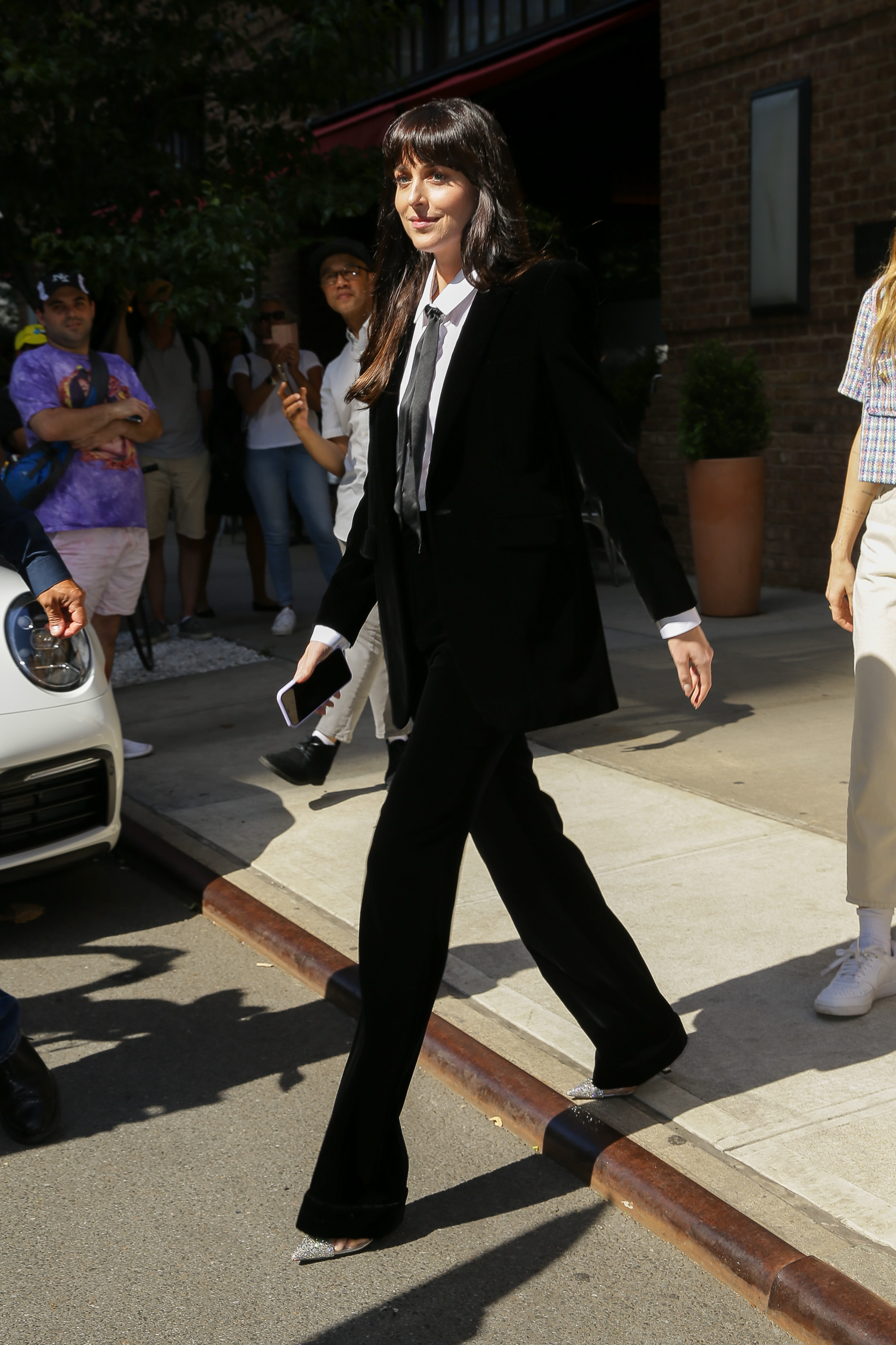 Dakota Johnson was photographed as she greeted fans waiting for her outside her hotel in New York.  The actress wore a black suit with a shirt and bow