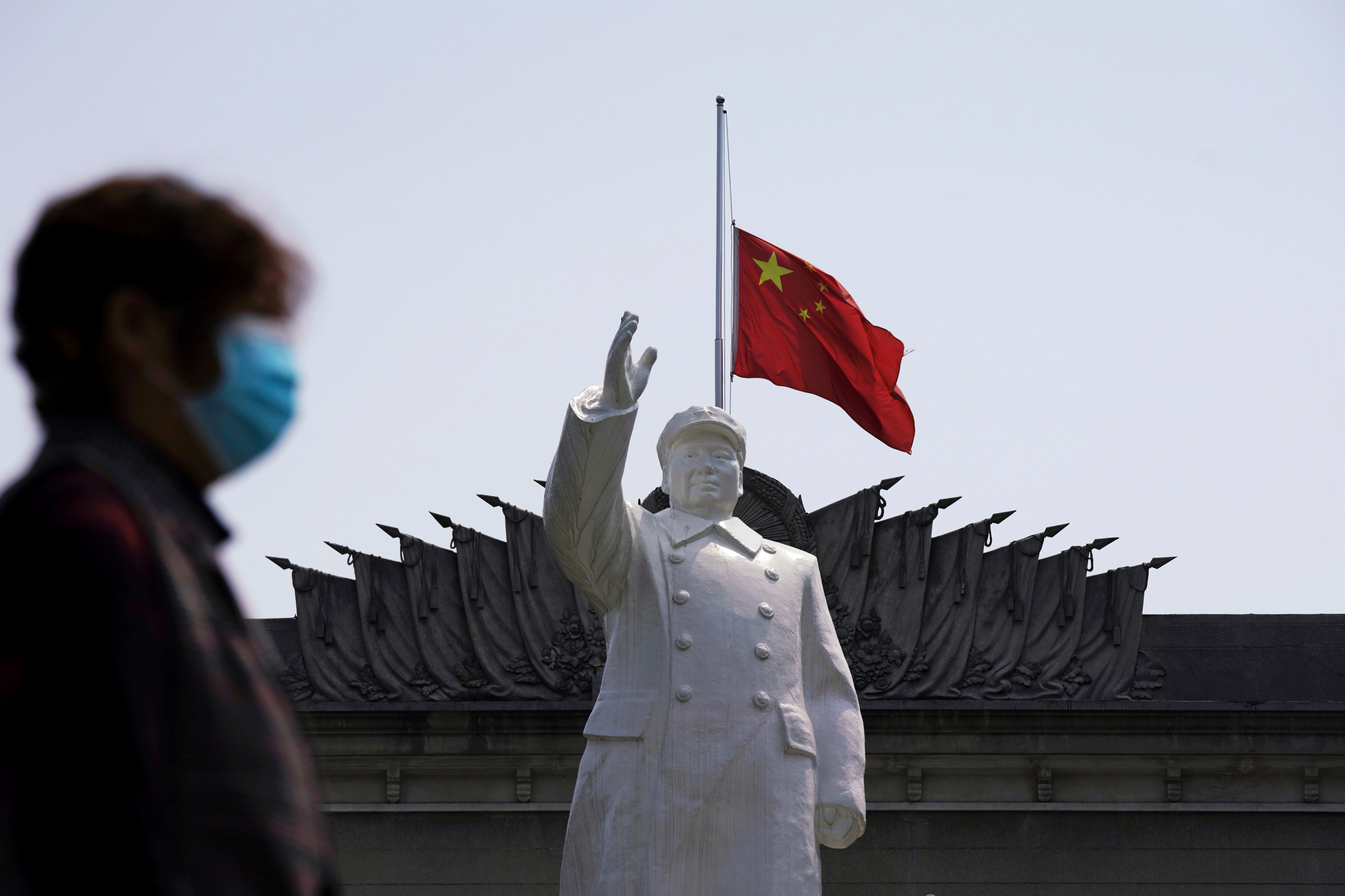 La bandera nacional china ondea a media asta detrás de una estatua del difunto dictador chino Mao Zedong en Wuhan, provincia de Hubei, el epicentro del coronavirus (Reuters)