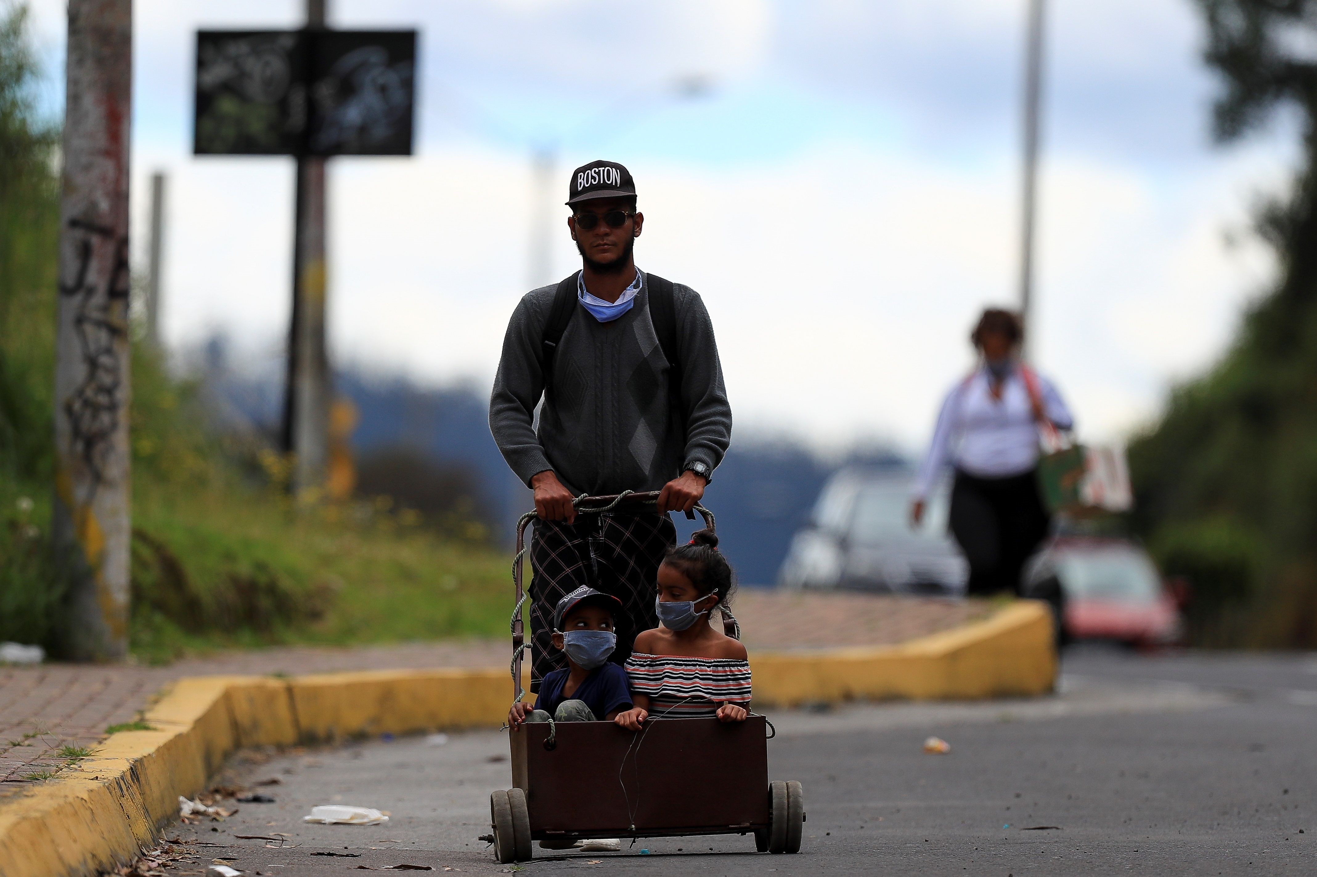 Un ciudadano venezolano y dos niños caminan por la carretera, de regreso a Venezuela (EFE/ José Jácome)
