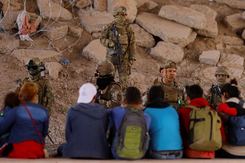 Migrantes son vistos cerca del río Bravo después de cruzar la frontera para pedir asilo en Estados Unidos, mientras miembros de la Guardia Nacional del Ejército de Texas montan guardia para inhibir el cruce de migrantes, visto desde Ciudad Juárez, México el 13 de mayo de 2023. REUTERS/Jose Luis González