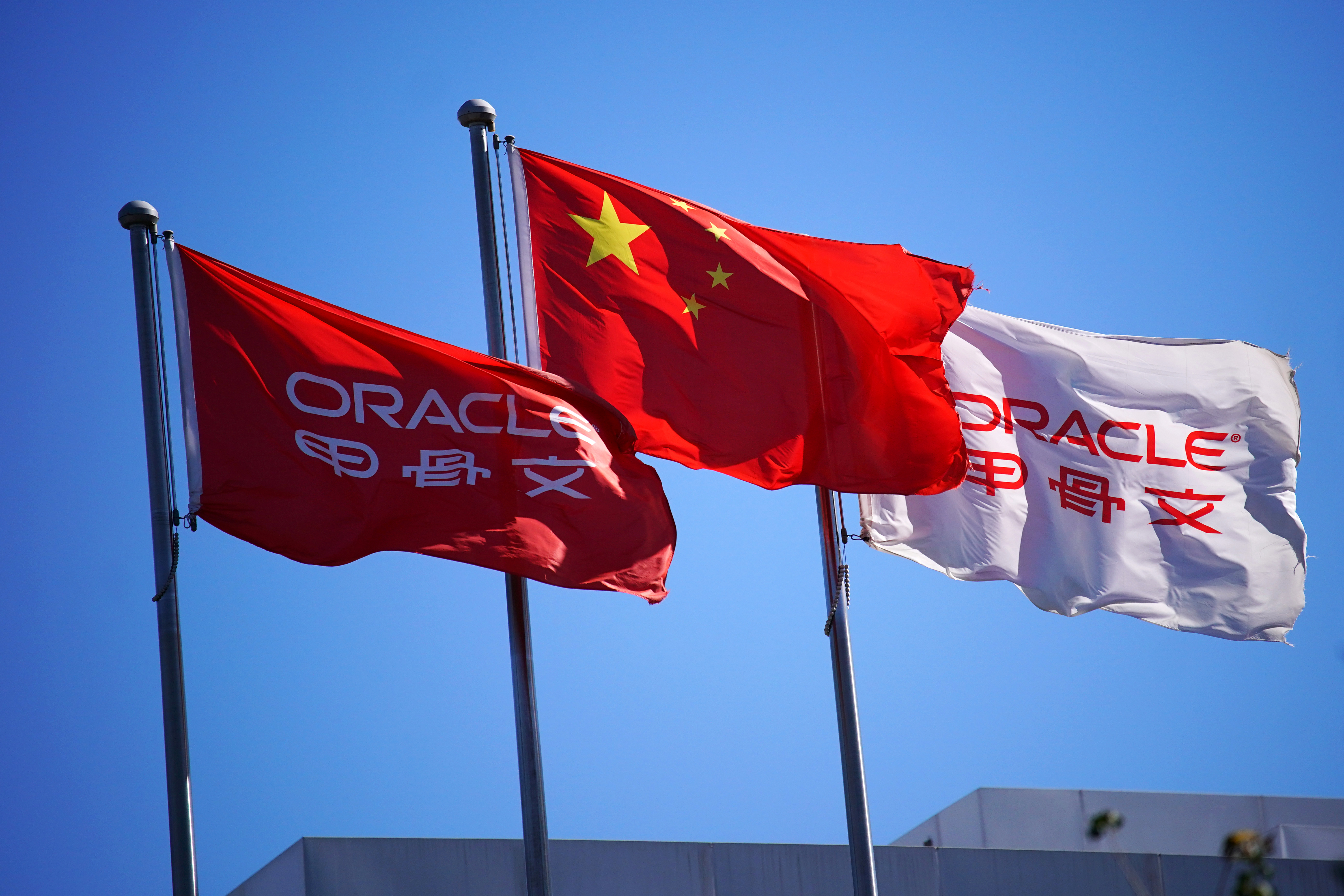 Una bandera nacional china ondea entre banderas de Oracle en sus edificios de oficinas en Beijing, China, 16 de septiembre de 2020. REUTERS/Tingshu Wang/Archivo