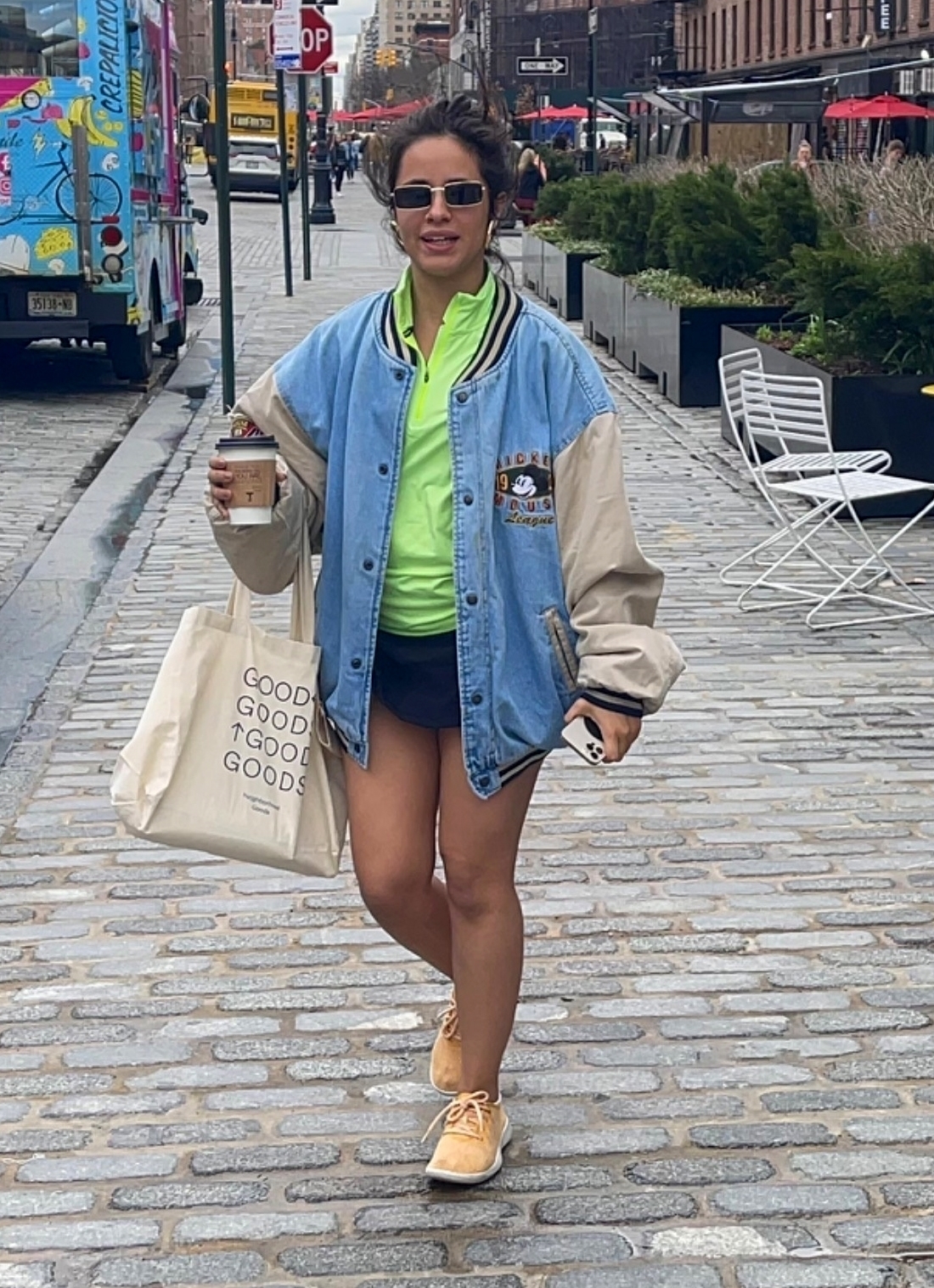 Camila Cabello fue fotografiada en un paseo comercial de Nueva York a donde había ido a comprar un café para llevar. Lució un look colorido: short azul, remera verde, campera de jean, zapatillas color mostaza. Completó su outfit con lentes de sol y una bolsa estampada de tela