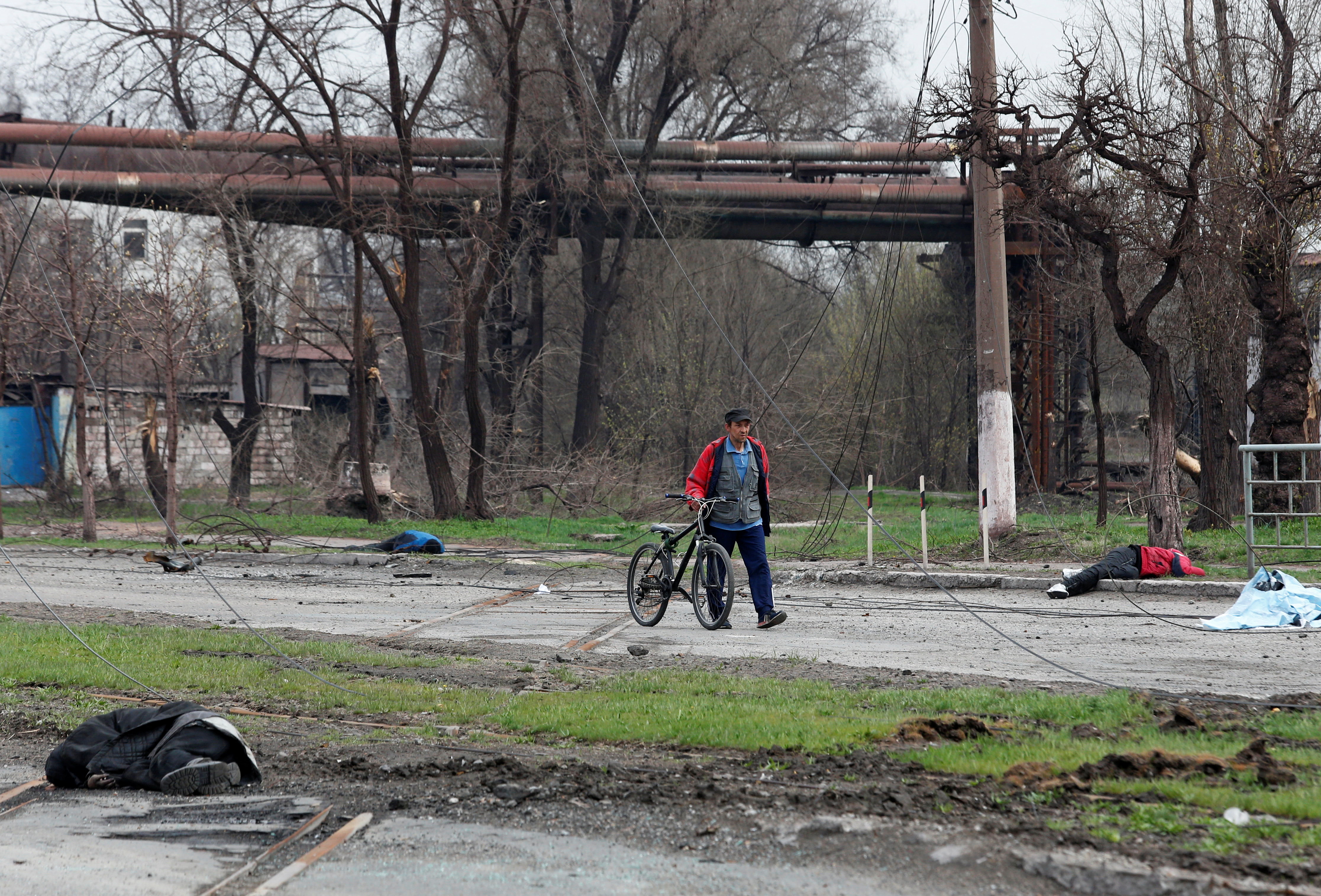 Un ucraniano camina por Mariupol junto a cuerpos de civiles asesinados por los rusos (REUTERS/Alexander Ermochenko)