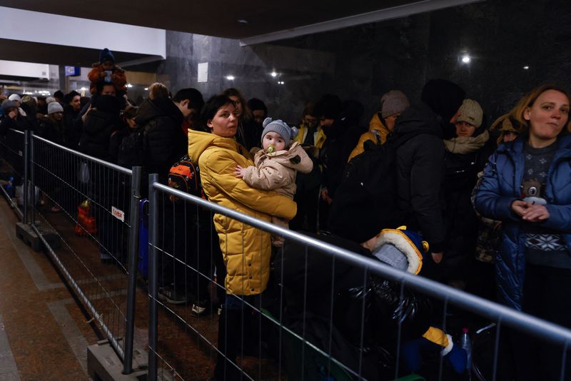 Una mujer sostiene un niño mientras personas huyen de la invasión de Rusia a Ucrania en la estación de trenes en Lviv (Reuters)