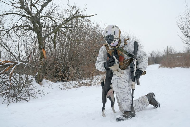 Un miembro del servicio de las fuerzas armadas ucranianas acaricia a un perro en las posiciones de combate cerca de la línea de separación de los rebeldes respaldados por Rusia en las afueras de la ciudad de Avdiivka en la región de Donetsk, Ucrania. 25 de enero de 2022. REUTERS/Maksim Levin