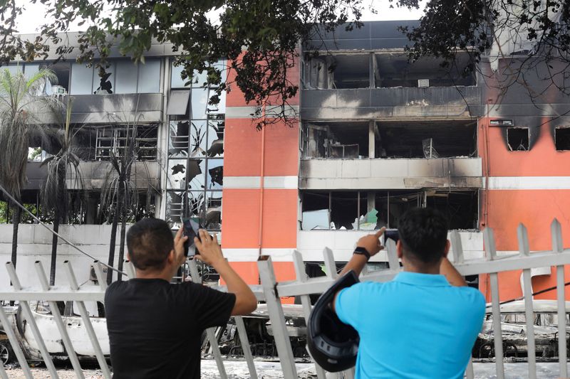 Hombres toman fotos del edificio de la Fiscalía General del Estado que fue dañado durante las protestas tras la detención del gobernador de Santa Cruz, Luis Fernando Camacho (REUTERS/Lesly Moyano)