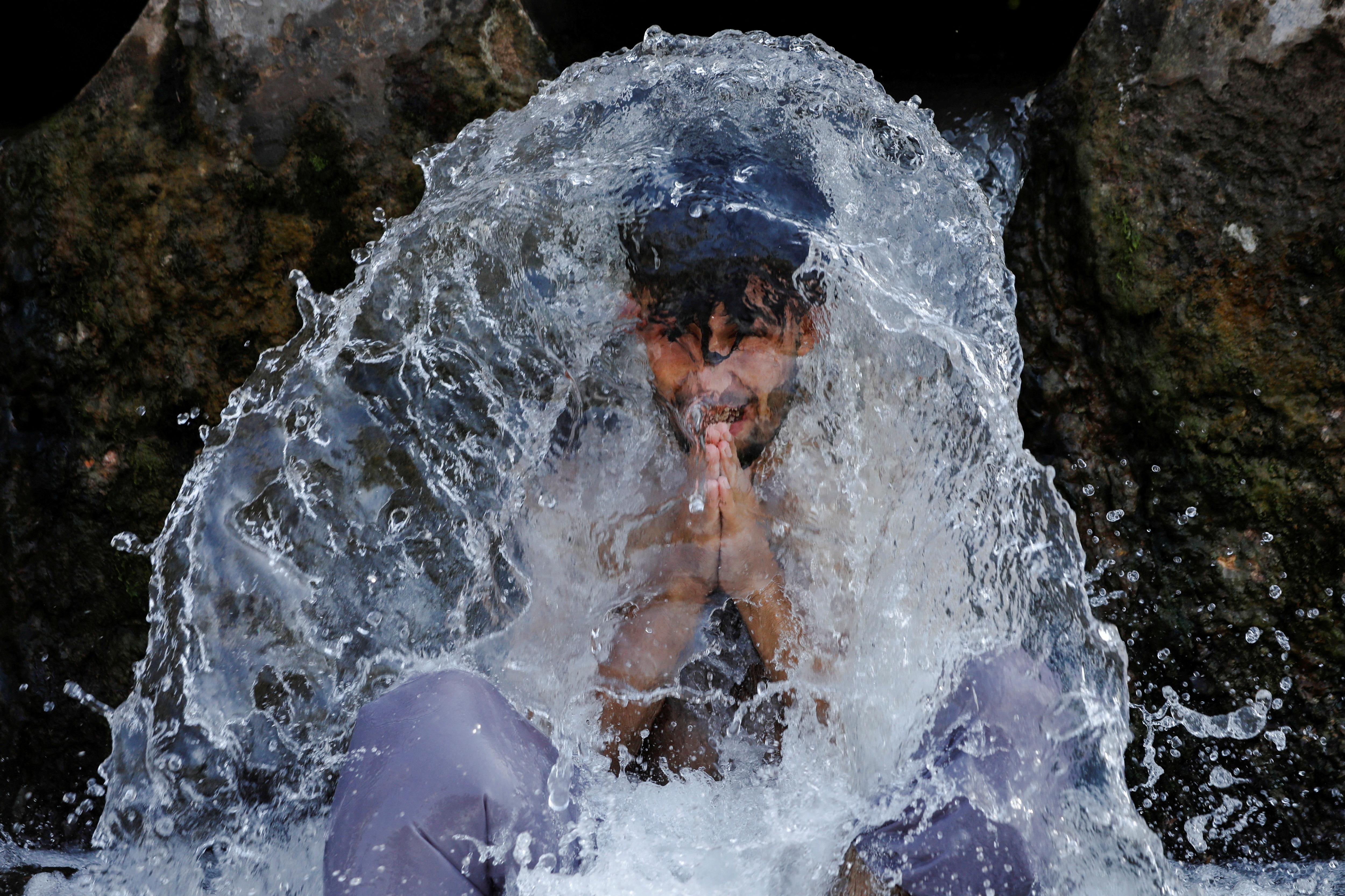 Un hombre reacciona mientras se enfría bajo una tubería de agua de un canal durante el clima cálido y húmedo, en las afueras de Peshawar, Pakistán, 21 de junio de 2023. REUTERS/Fayaz Aziz IMÁGENES TPX DEL DÍA