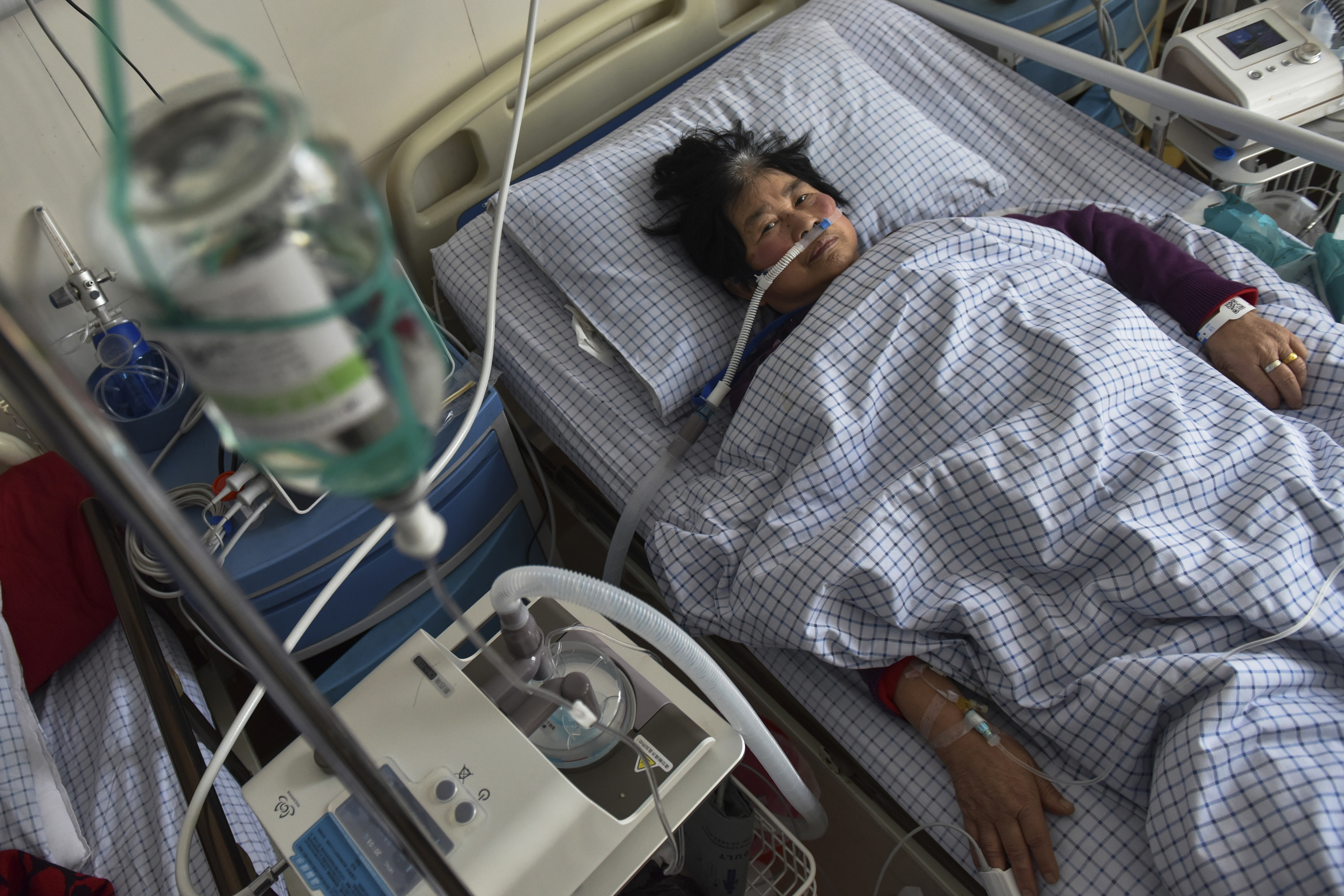 A woman with COVID symptoms receives an intravenous drip while using a ventilator in the emergency room of a hospital in Fuyang, in the central Chinese province of Anhui (Chinatopix Via AP)