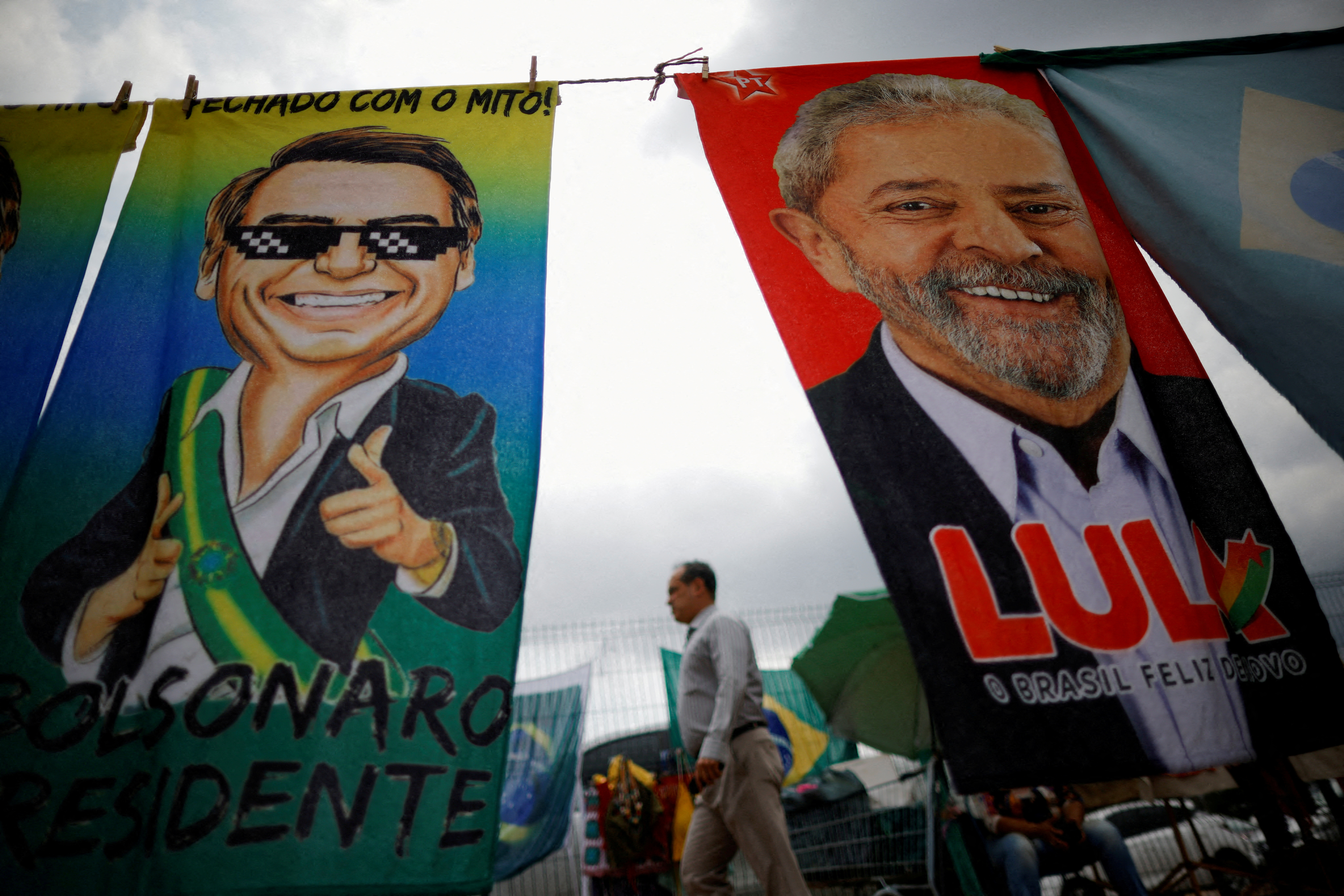FILE PHOTO: A man walks past election campaign flags depicting former President Lula da Silva and current President Jair Bolsonaro in Brasilia (REUTERS/Adriano Machado)