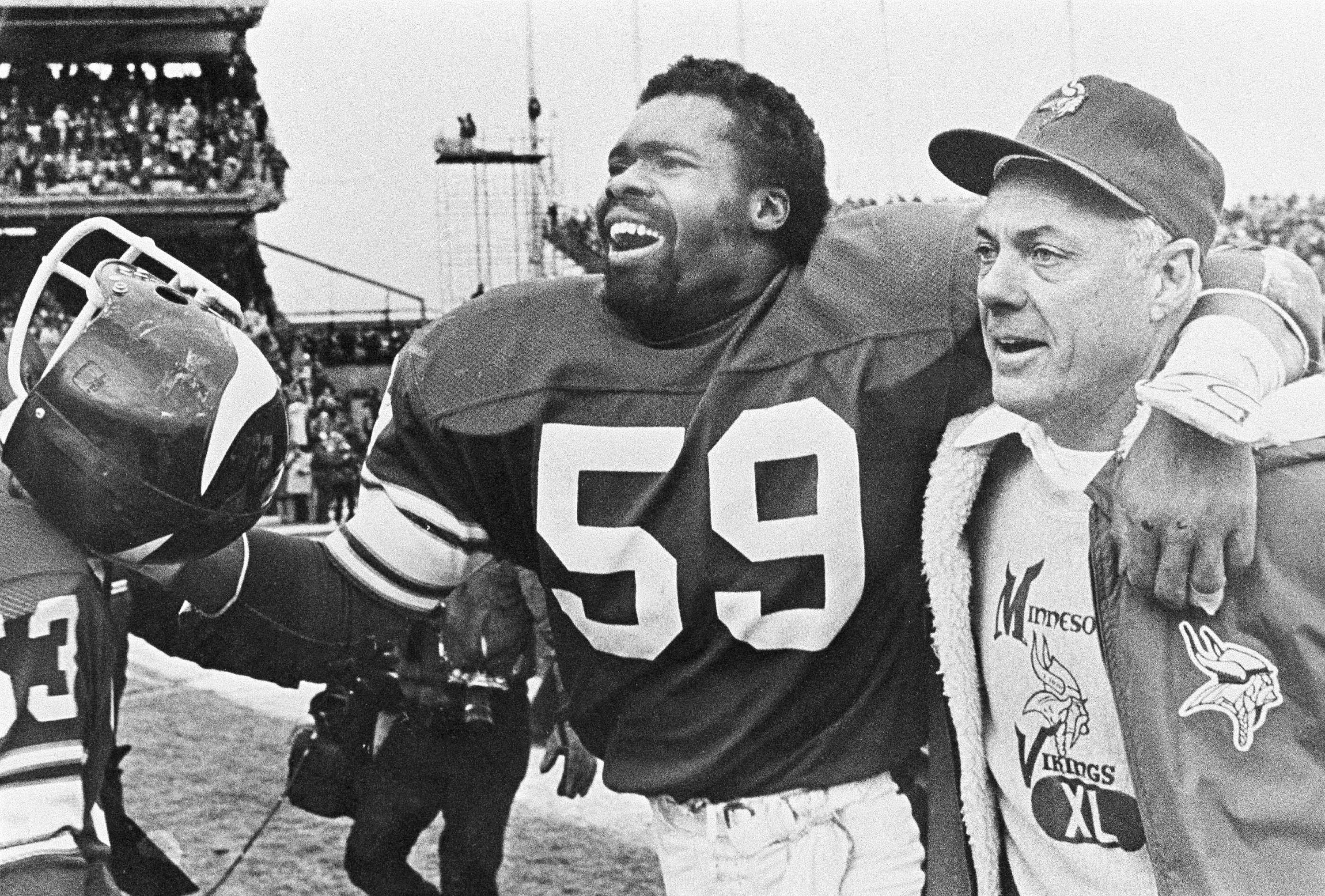 FILE - In this Dec. 14, 1980 photo, Minnesota Vikings coach Bud Grant smiles as he walks into the locker room with his arms around linebacker Matt Blair after beating the Cleveland Browns.  On Saturday, March 11, 2023, Grant passes away at the age of 95.  (AP Photo/File)
