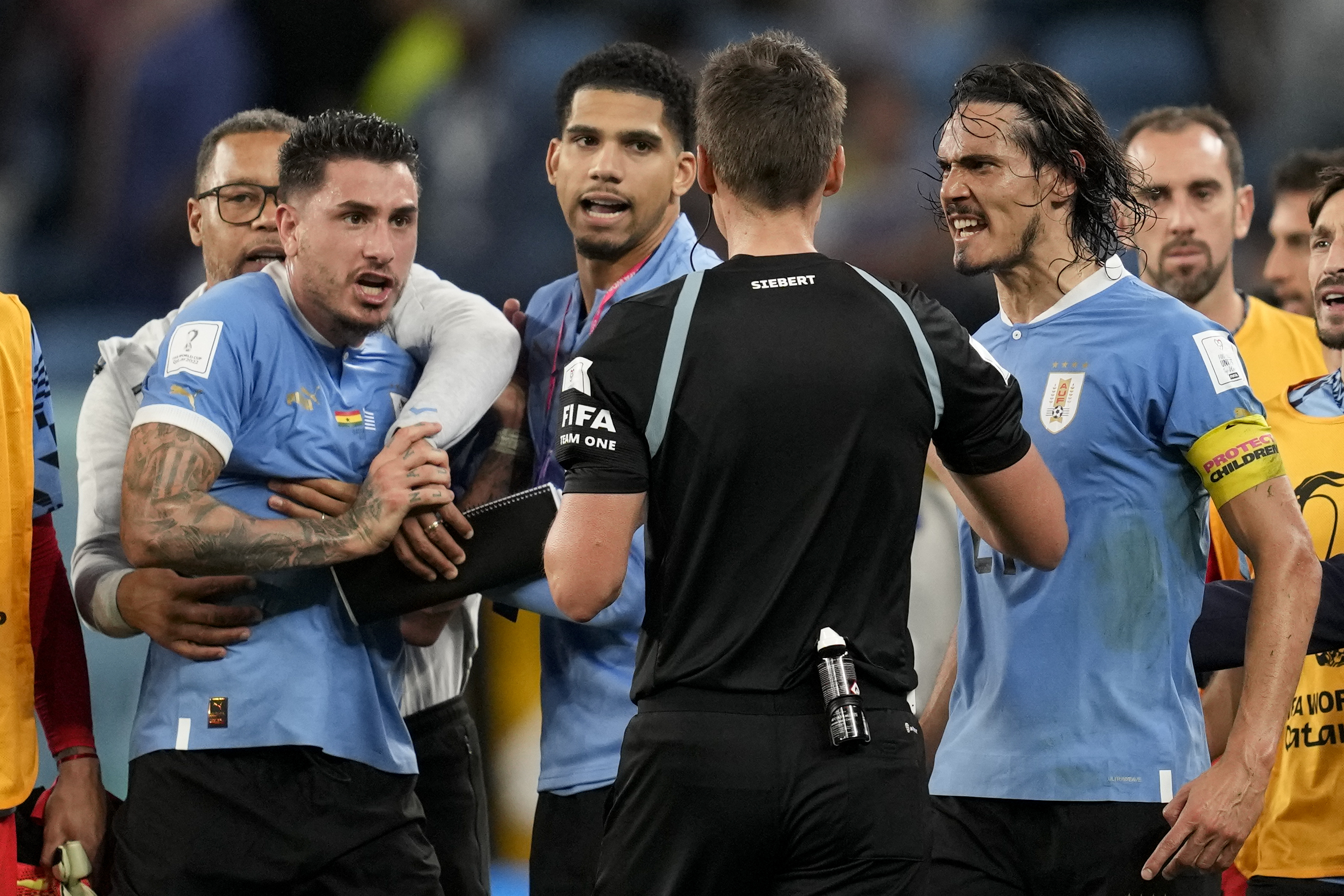 ARCHIVO - Foto del 2 de diciembre del 2022, Edinson Cavani discute con el árbitro alemán Daniel Daniel Siebert of Germany al final del encuentro ante Ghana en la Copa Mundial. El viernes 27 de enero del 2023, la FIFA suspende a los uruguayos Fernando Muslera y José María Giménez por cuatro partidos y a los veteranos Cavani y Diego Godín un duelo más cada uno por confrontar de manera agresiva a los árbitros cuando el equipo fue eliminado el mes pasado de la Copa Mundial. (AP Foto/Darko Vojinovic, File)