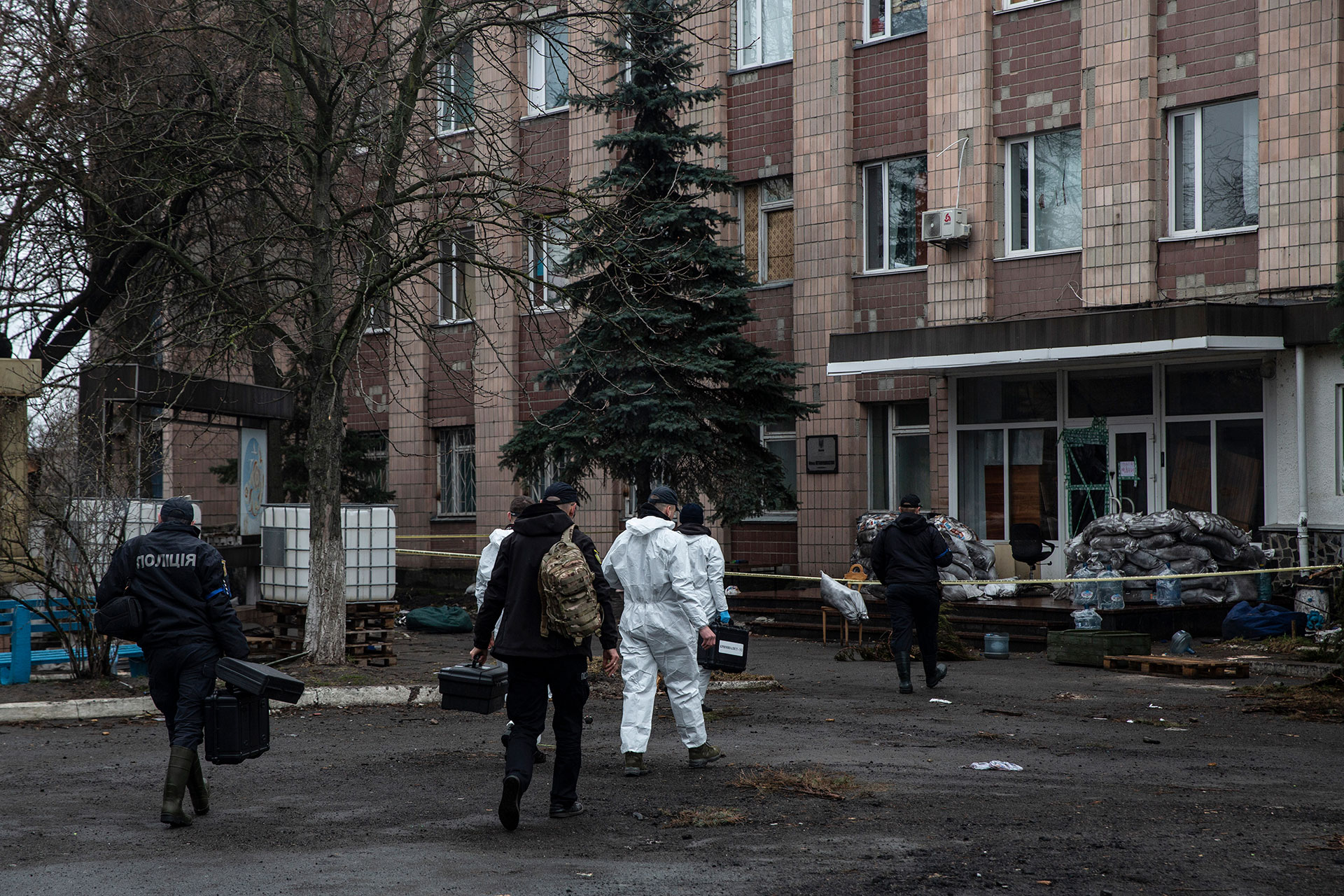 Investigadores ucranianos entran en un edificio el 9 de abril que fue ocupado por las fuerzas rusas. Detrás del edificio, el 3 de abril, se encontraron cadáveres de hombres con signos de tortura y ejecución. (Foto para The Washington Post por Heidi Levine)