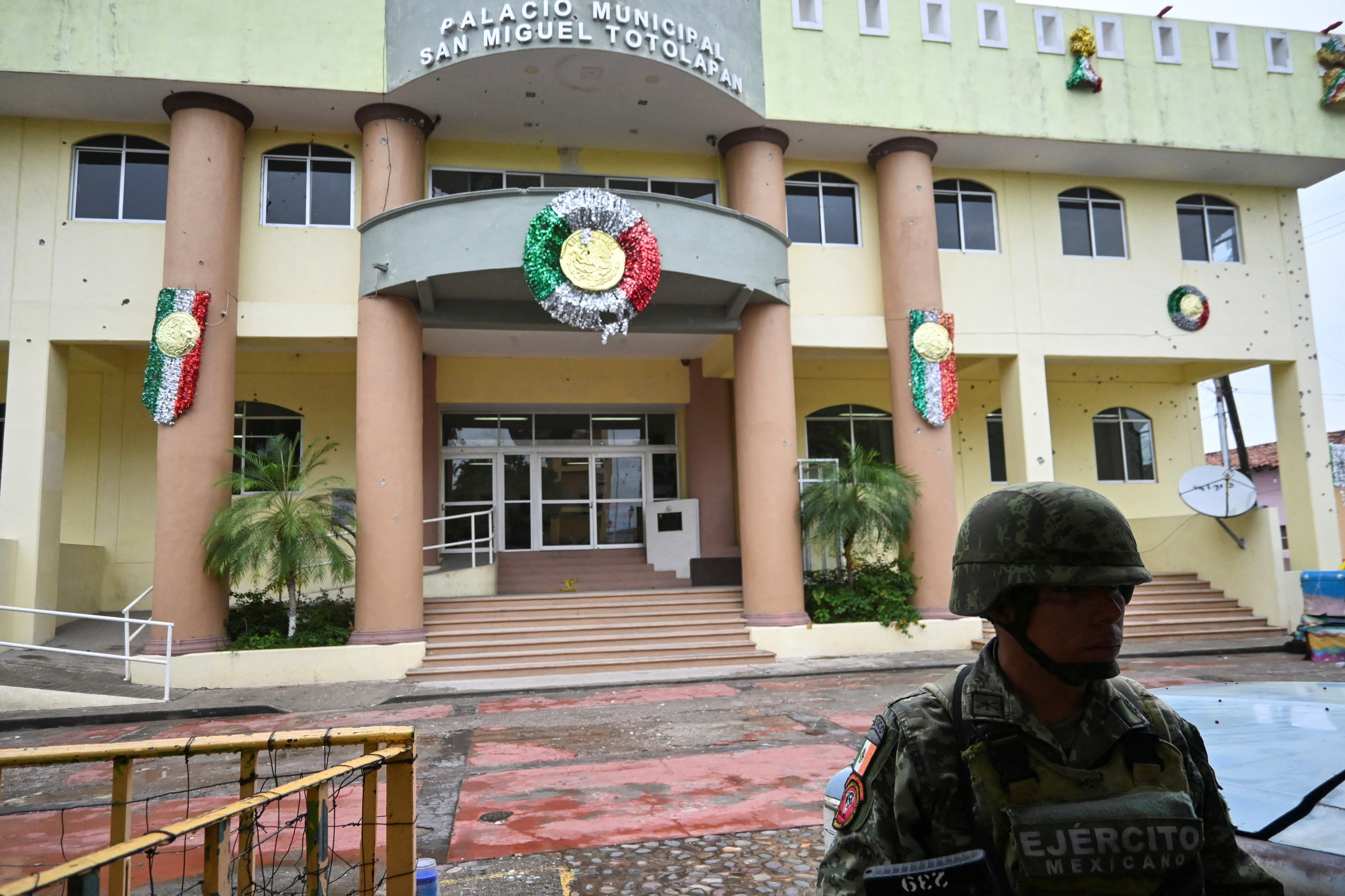 A member of security forces stands guard outside the facade of the town hall with several shots on wall, after a fight between rival gangs left several dead, in San Miguel Totolapan, state of Guerrero, Mexico October 6, 2022. REUTERS/Lenin Ocampo NO RESALES. NO ARCHIVES