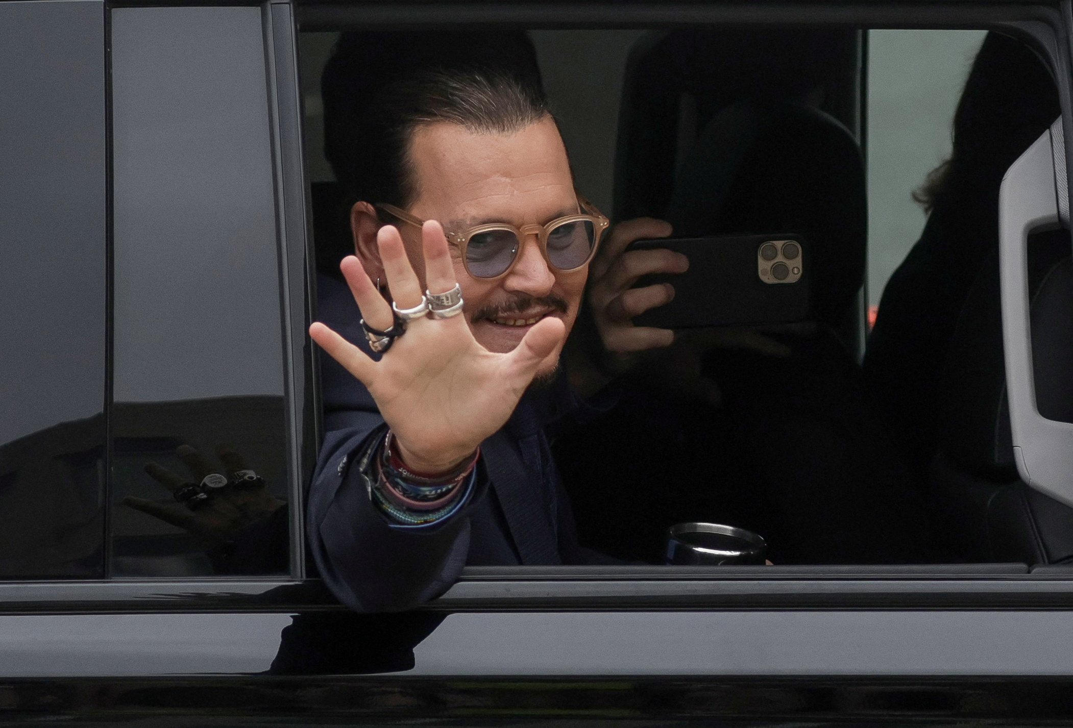 Johnny Depp saluda a sus fans que lo esperan en la salida del tribunal de Fairfax, Virginia (Reuters)