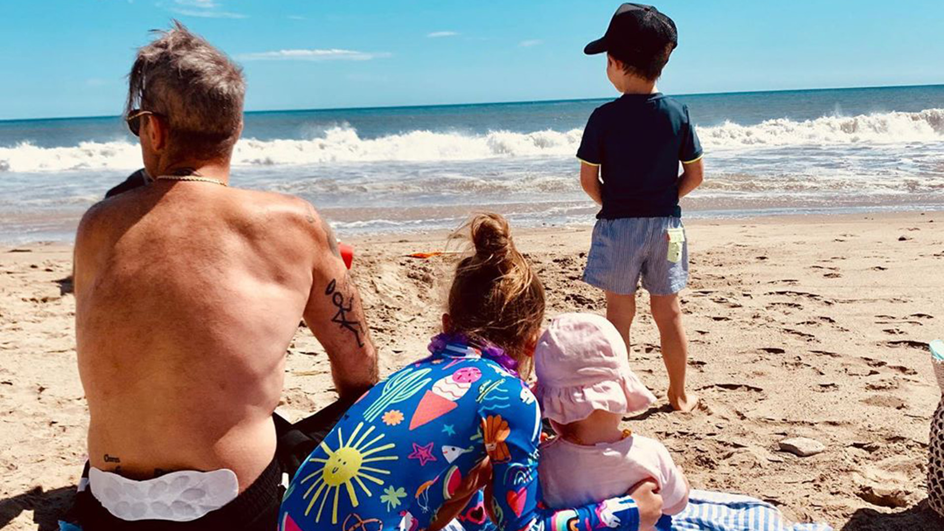 Robbie Williams con sus hijos en la playa.