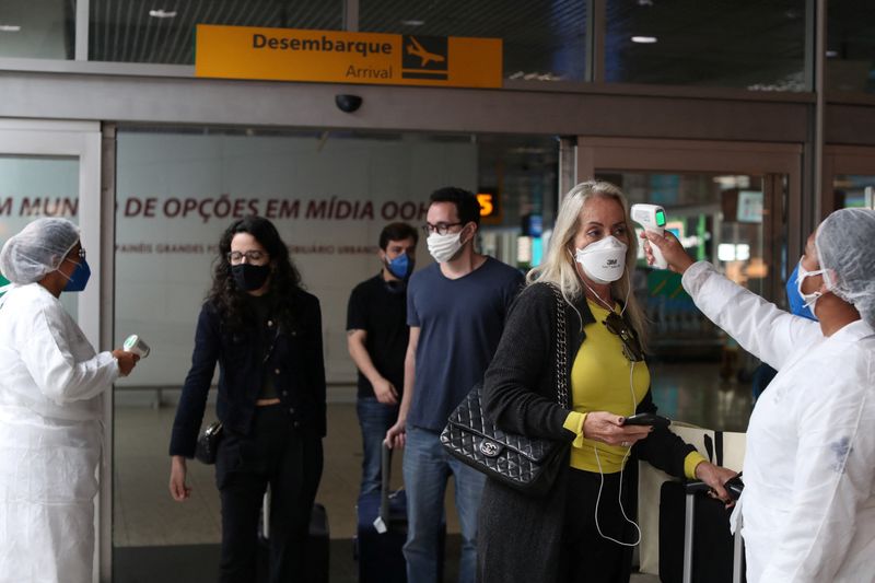 Una trabajadora de salud tomando la temperatura de una persona que ingresa a Brasil a través del aeropuerto Congonhas de San Pablo (REUTERS/Amanda Perobelli/Archivo)