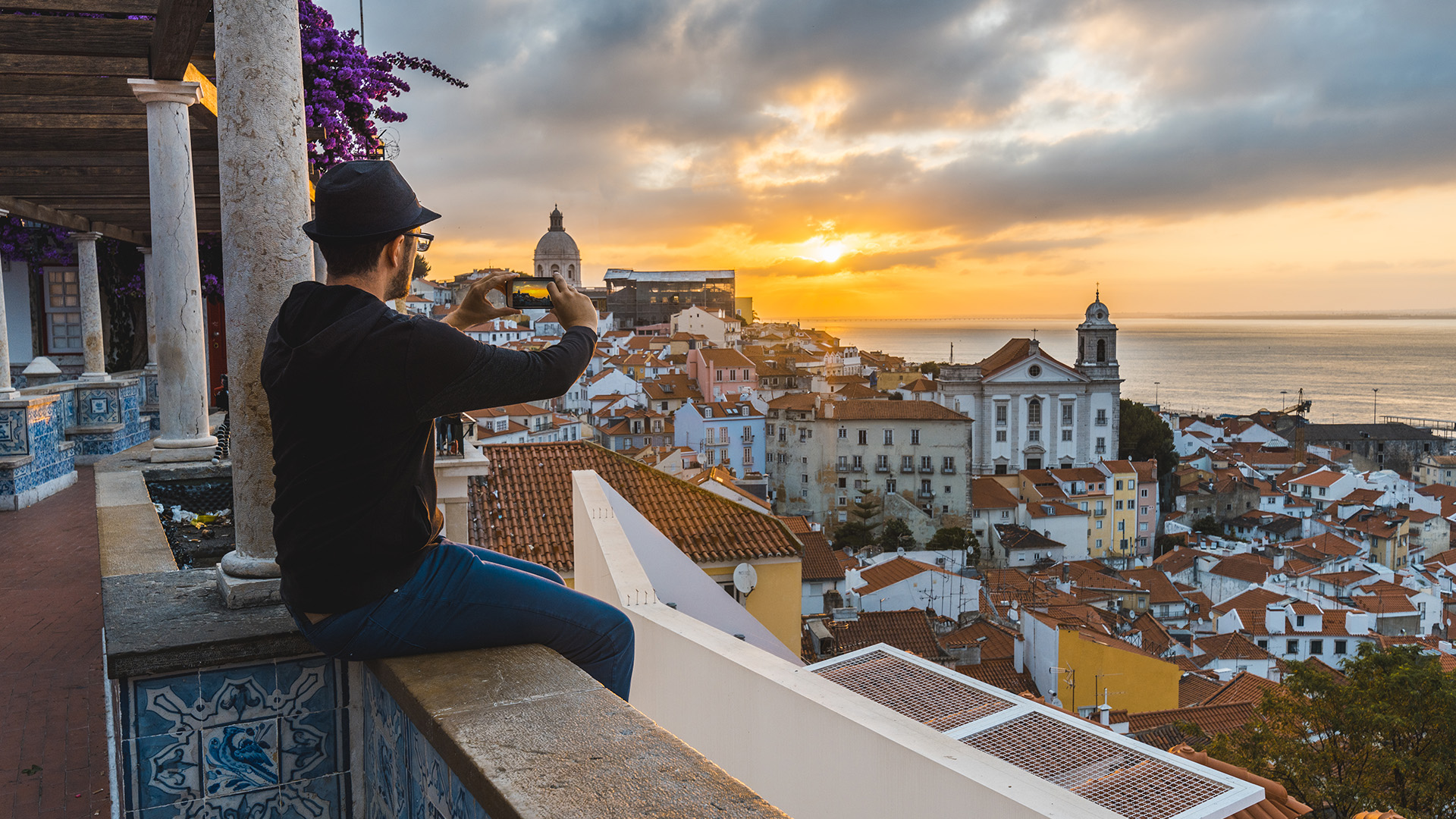 Un joven toma una fotografía de un atardecer sobre la ciudad de Lisboa. (Getty Images)