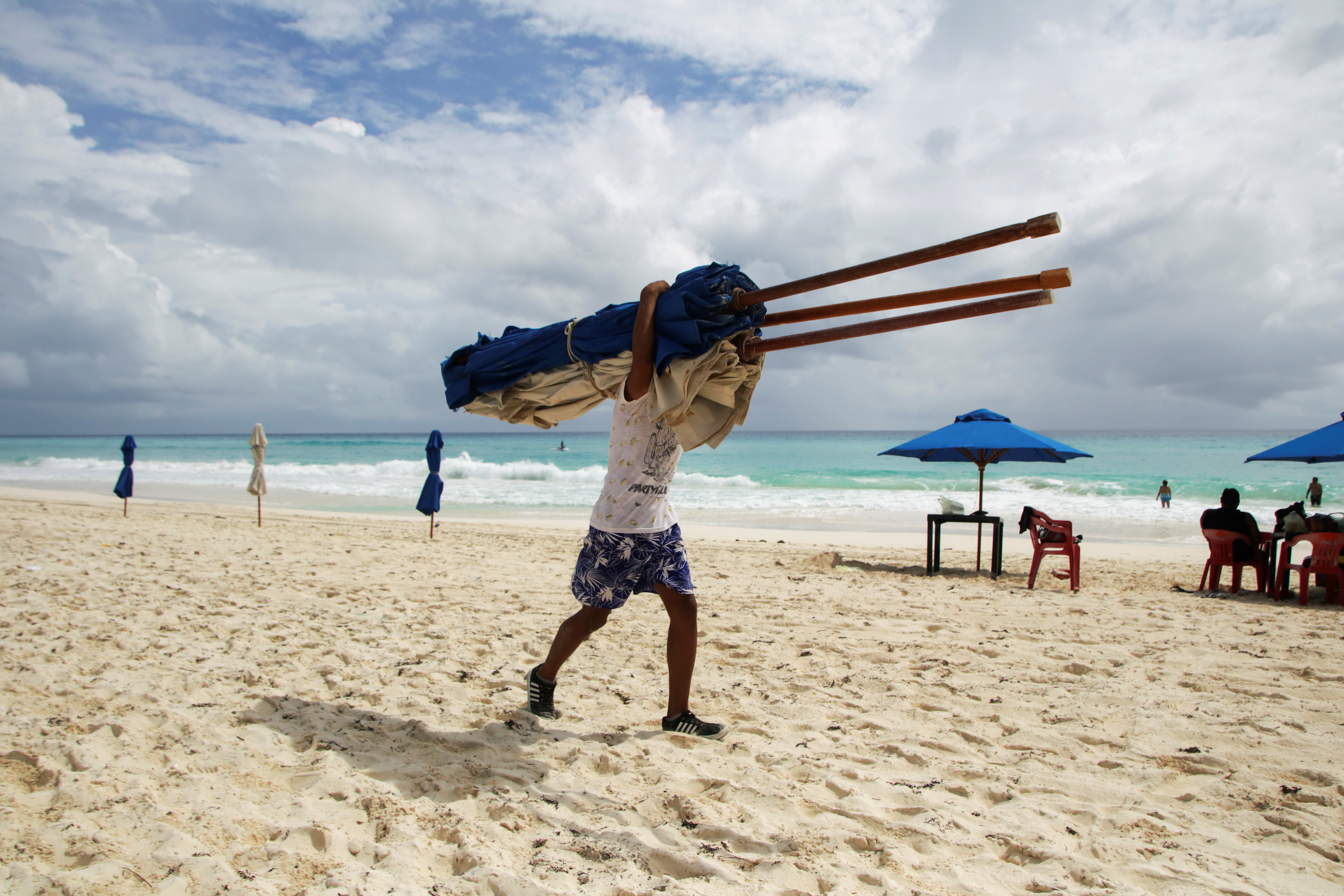 A hotel employee removes beach umbrellas from a beach in preparation for the arrival of Hurricane Delta, in Cancun, Mexico October 6, 2020. REUTERS/Jorge Delgado