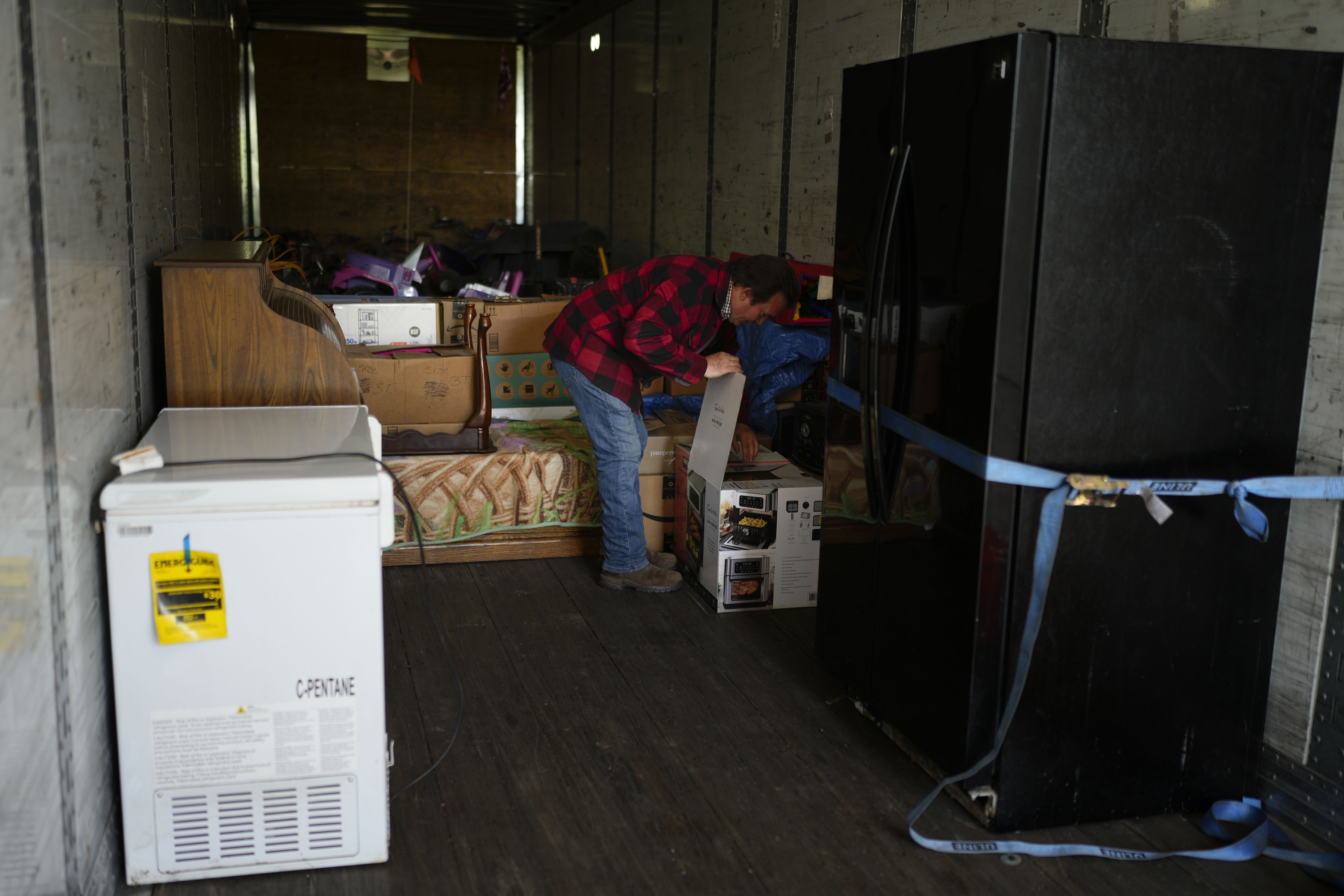 Ron Caetano opens a box in a trailer where he placed his family's belongings as a flood precaution, in Lemoore, Calif., Wednesday, April 19, 2023. (AP Photo/Jae C. Hong)