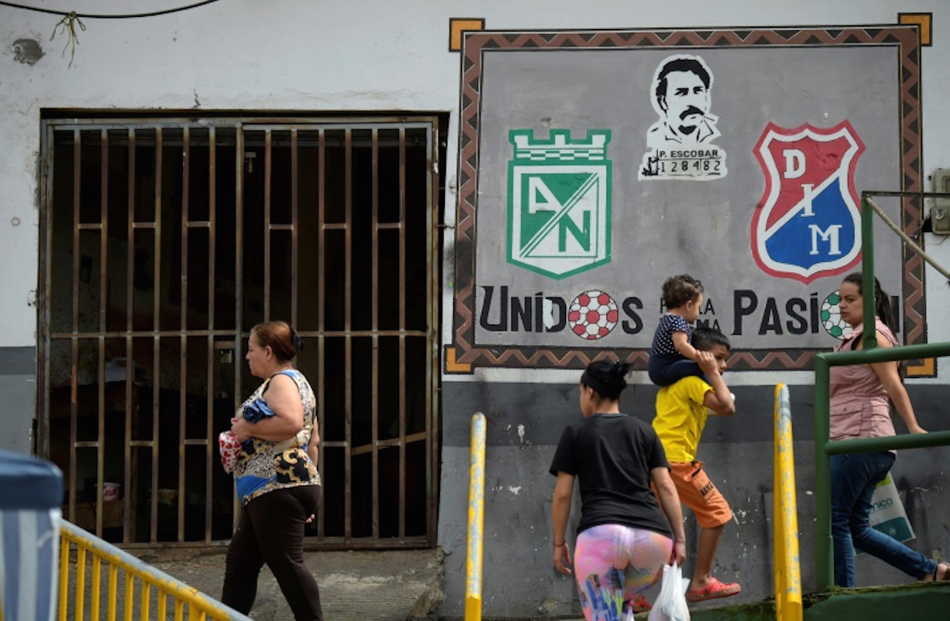 Vecinos del barrio Pablo Escobar pasan por delante de una pintura con la cara del capo del narcotráfico, el 28 de noviembre de 2018, en Medellín, Colombia (AFP - Raul ARBOLEDA)  
